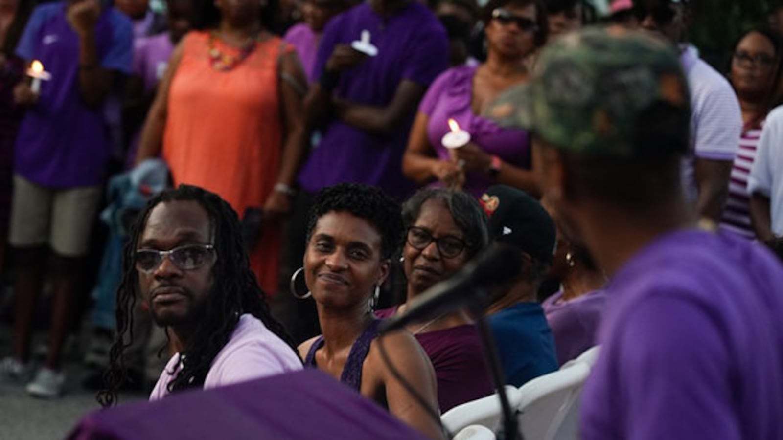 Imani Bell's parents look on as the teen's former coach speaks during Wednesday candlelight vigil.