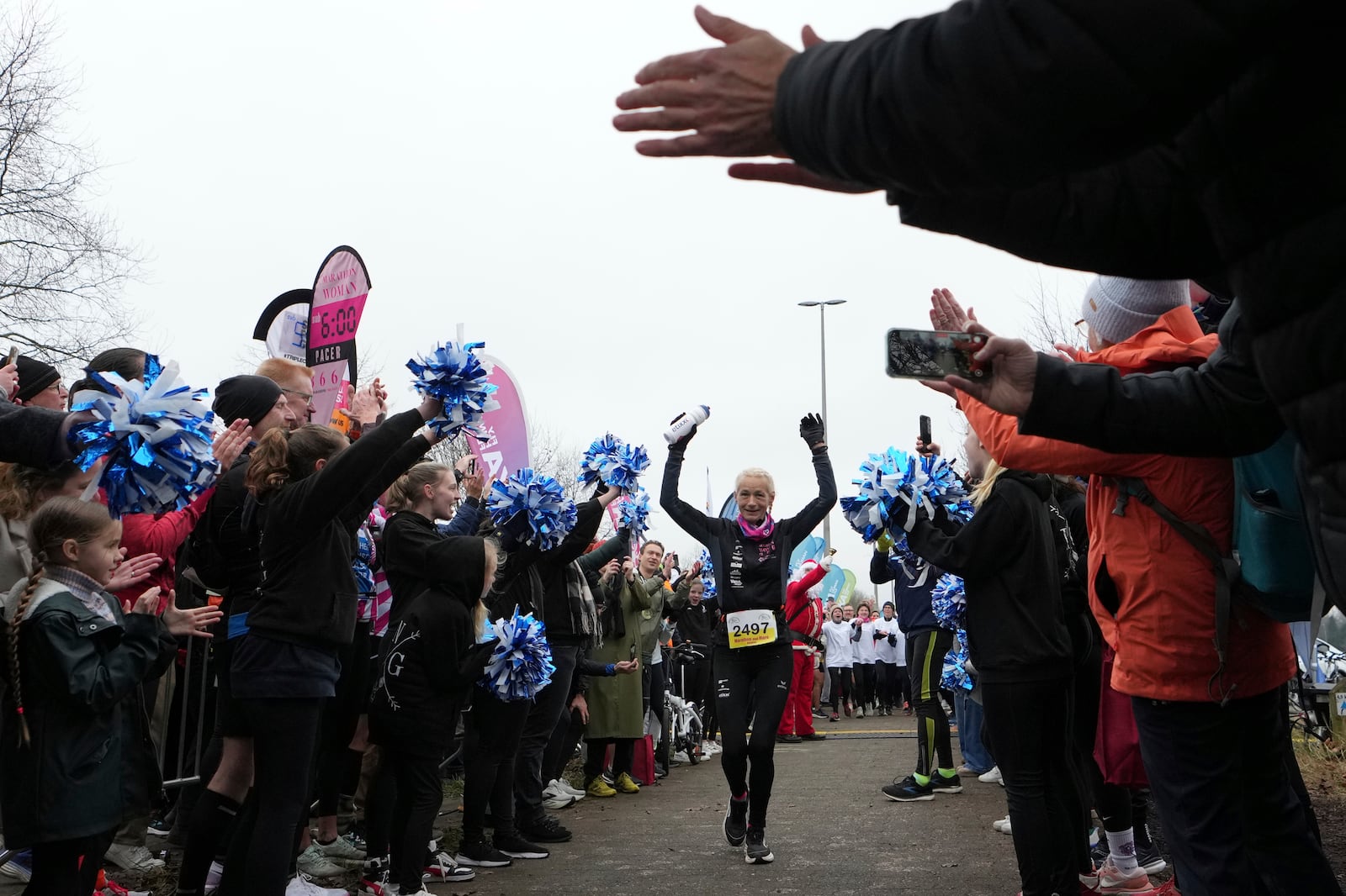 Belgian ultra runner Hilde Dosogne, center, is cheered on as she crosses the finish line during her 366th consecutive marathon in Ghent, Belgium, Tuesday, Dec. 31, 2024. (AP Photo/Virginia Mayo)