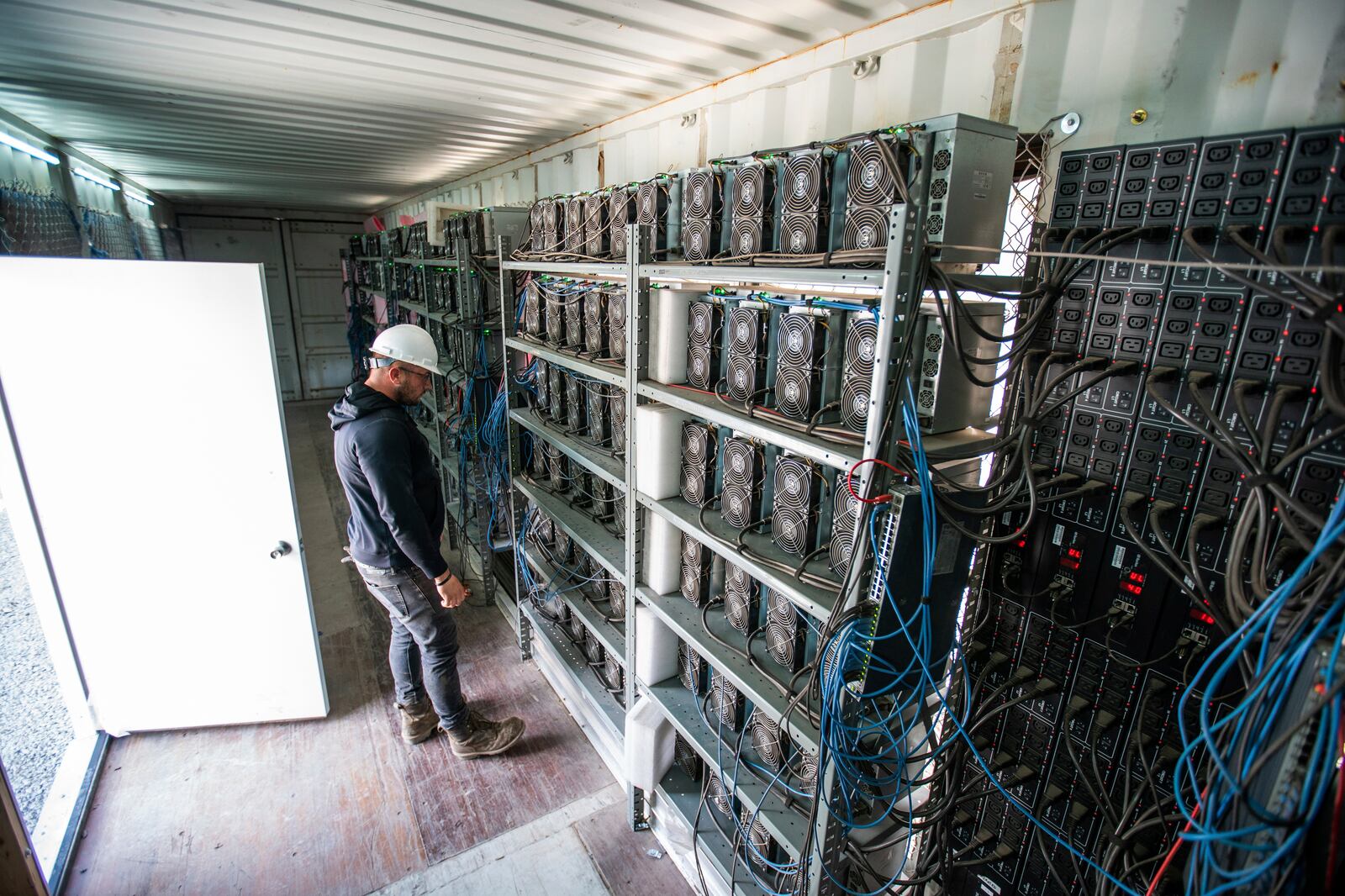 Chris Radwanski, data center supervisor, checks on bitcoin mining machines in a shipping container behind the Scrubgrass Power plant on Friday, July 23, 2021, in Russellton, Pa. (Andrew Rush/Pittsburgh Post-Gazette via AP)