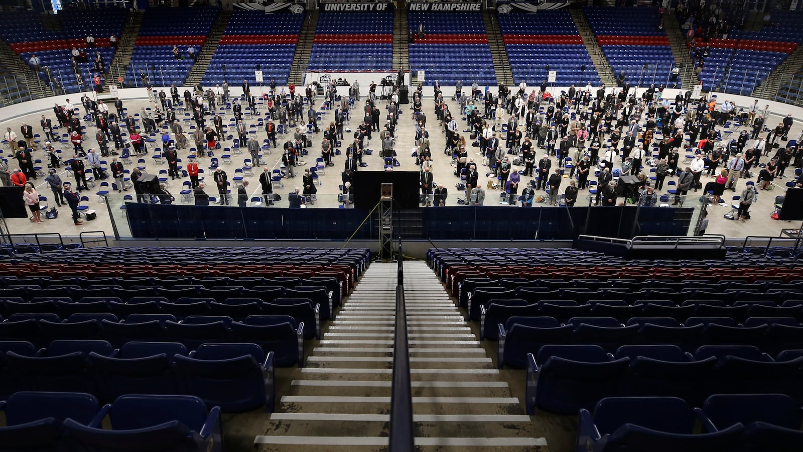 FILE - Members of the New Hampshire House of Representatives stand at the start of their session in Durham, N.H. on at the Whittemore Center at the University of New Hampshire, June 11, 2020. The Legislature, which suspended its work in March because of the COVID-19 virus outbreak, gathered at the arena for the first House session held outside the Statehouse since the Civil War. (AP Photo/Charles Krupa, File)