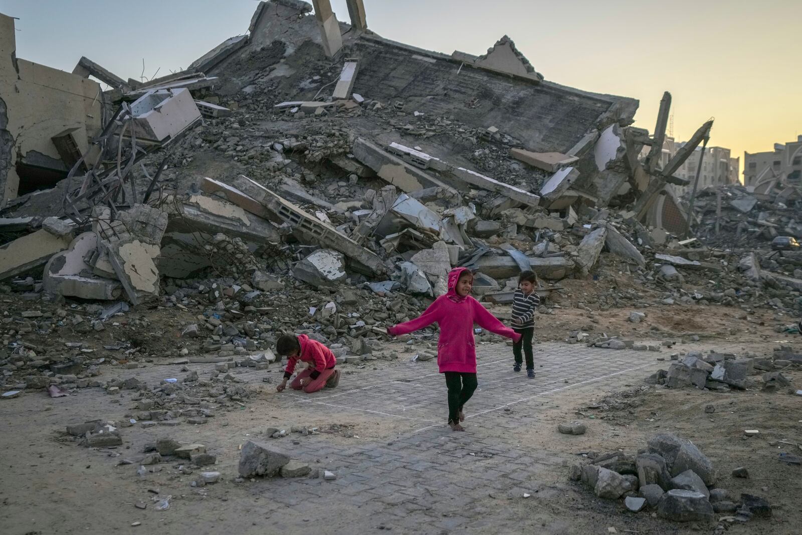 FILE - Palestinian children play next to a building destroyed by Israeli army strikes in the central Gaza Strip town of Khan Younis, Wednesday, Jan. 1, 2025. (AP Photo/Abdel Kareem Hana, File)