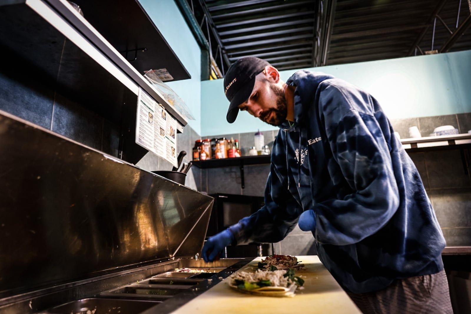 Flavors Eatery chef Travis Campbell prepares lunches for customers Tuesday July 9, 2024. JIM NOELKER/STAFF