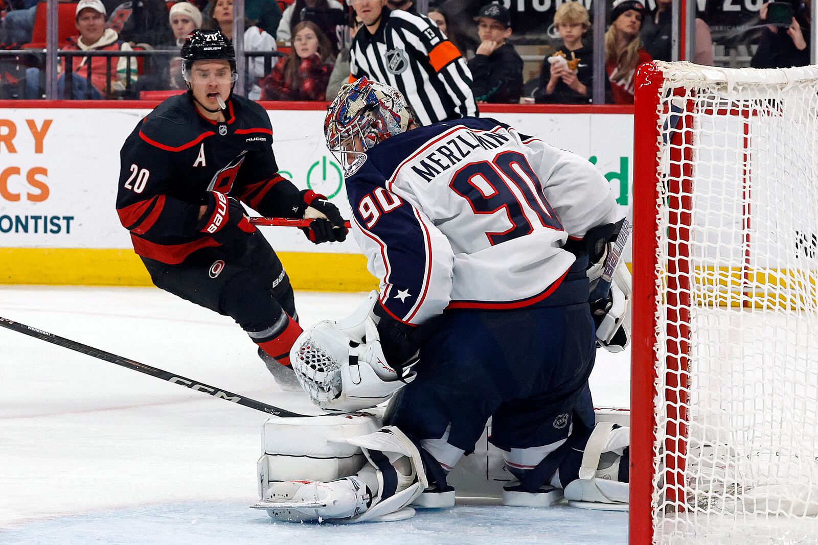 Columbus Blue Jackets goaltender Elvis Merzlikins (90) gathers in a shot from Carolina Hurricanes' Sebastian Aho (20) during the second period of an NHL hockey game in Raleigh, N.C., Sunday, Dec. 15, 2024. (AP Photo/Karl B DeBlaker)