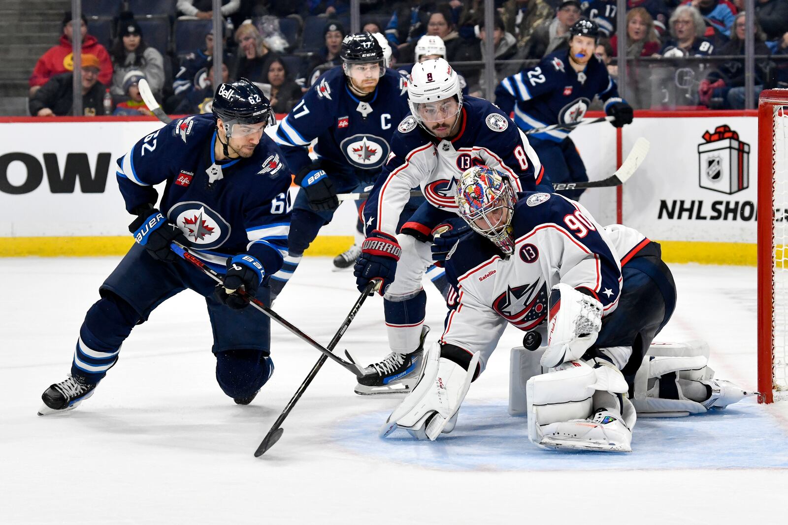 Columbus Blue Jackets' goaltender Elvis Merzlikins (90) makes a save on Winnipeg Jets' Nino Niederreiter (62) during the second period of an NHL hockey game in Winnipeg, Canada Sunday, Dec. 8, 2024. (Fred Greenslade/The Canadian Press via AP)