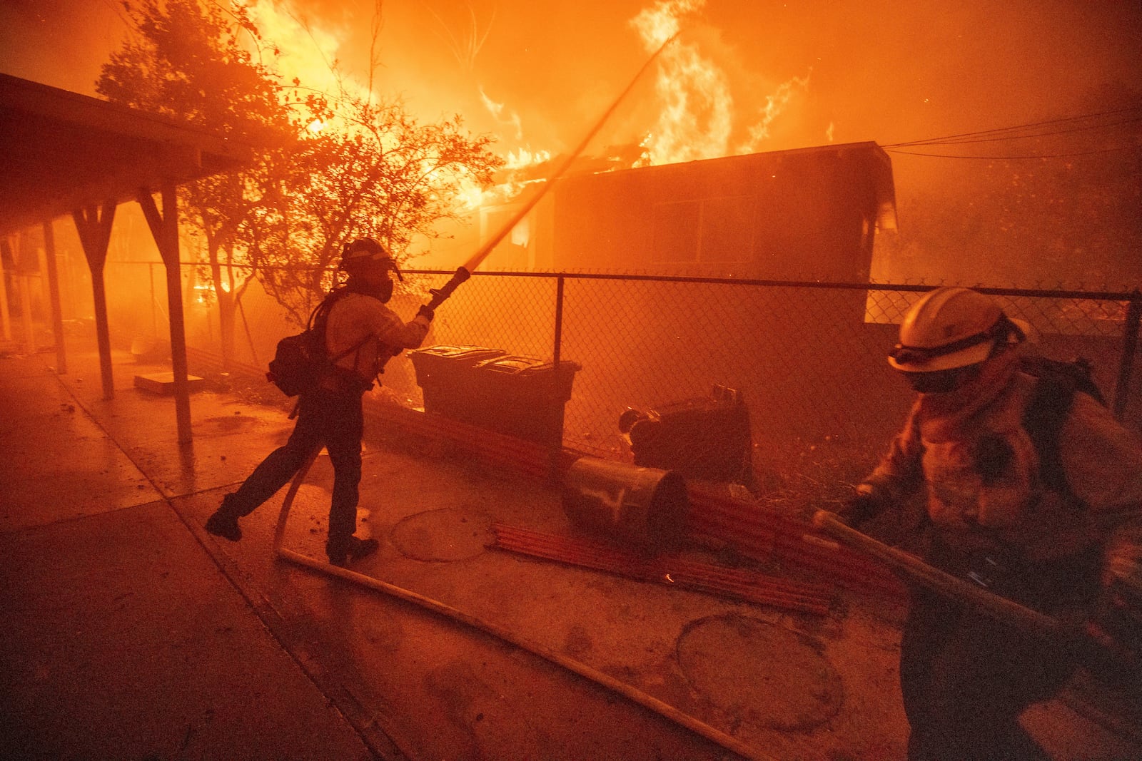 FILE - Firefighters protect a structure as the Eaton Fire advances, Jan. 8, 2025, in Altadena, Calif. (AP Photo/Ethan Swope, File)