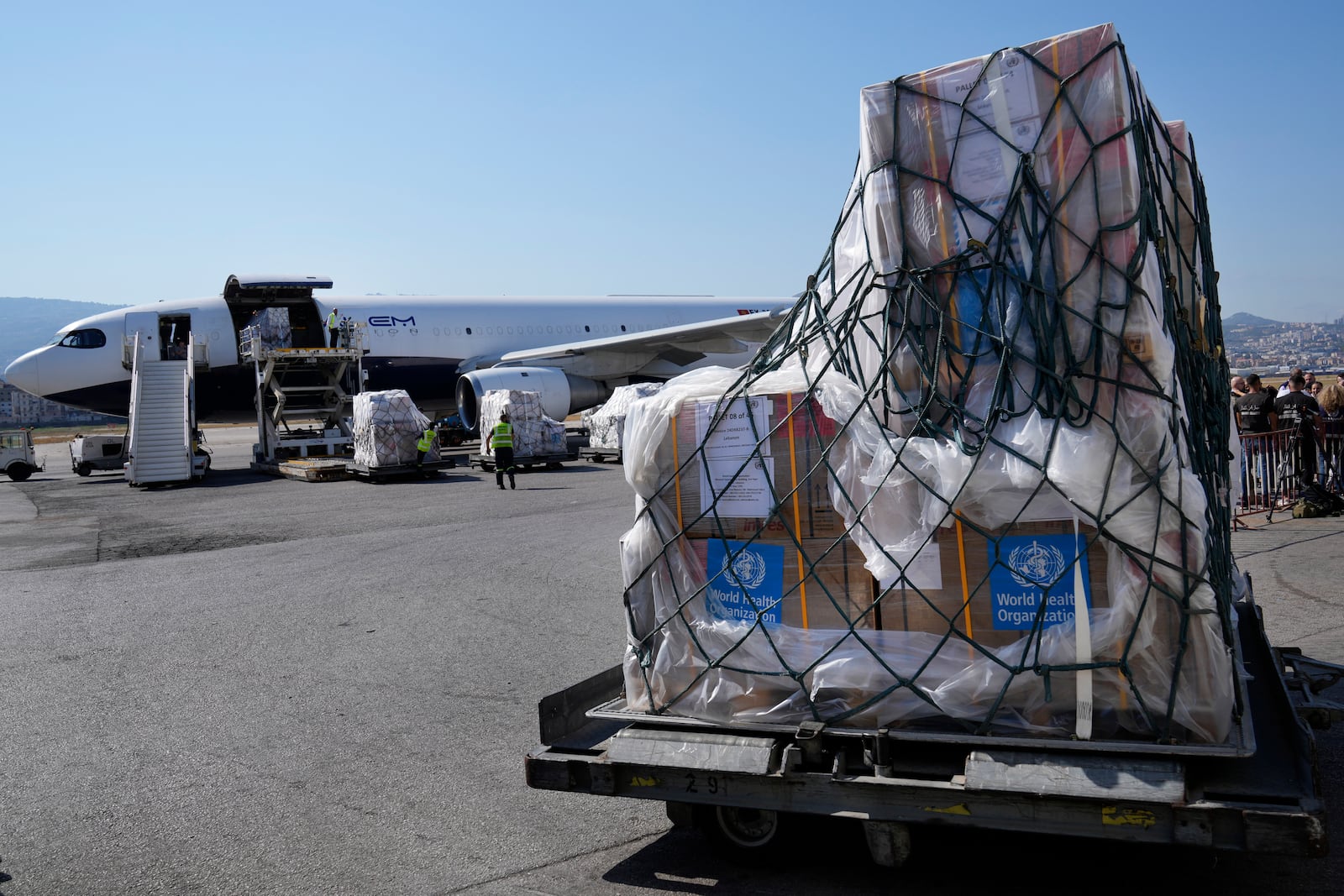 FILE - Airport workers, background, unload from a plane boxes of medical aid, which are part of preparedness by the medical sector in Lebanon in case an all-out war breaks out between Isreal and Hezbollah, at Rafik Hariri International Airport in Beirut, Lebanon, Monday, on Aug. 5, 2024. (AP Photo/Hussein Malla, File)