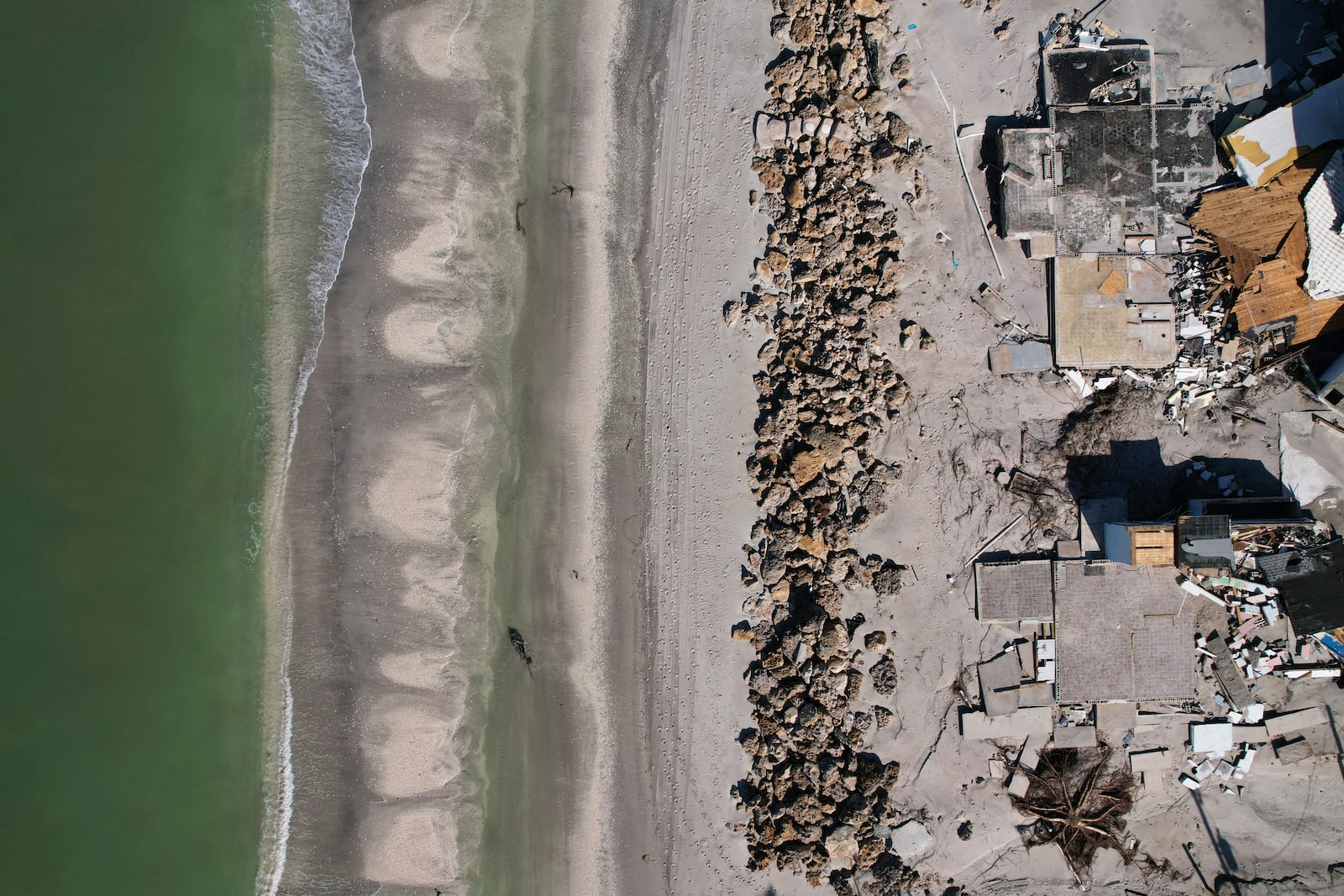 Waves lap on the beach in front of empty house foundations surrounded by debris, following the passage of Hurricane Milton, on Manasota Key, in Englewood, Fla., Sunday, Oct. 13, 2024. (AP Photo/Rebecca Blackwell)