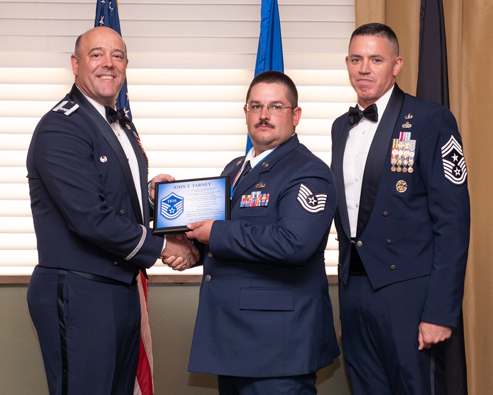 Col. Patrick Miller (left), 88th Air Base Wing and installation commander, presents a master sergeant promotion plaque to an Airman during the Senior Noncommissioned Officer Induction Ceremony on July 23 at Wright-Patterson Air Force Base. At right is Chief Master Sgt. Jason Shaffer, 88 ABW command chief. U.S. AIR FORCE PHOTO/WESLEY FARNSWORTH