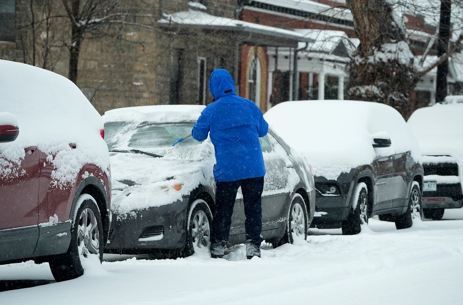 A motorist clears ice and snow from the windshield of a vehicle as a winter storm sweeps over the intermountain West, plunging temperatures into the single digits and bringing along a light snow in its wake Saturday, Jan. 18, 2025, in Denver. (AP Photo/David Zalubowski)