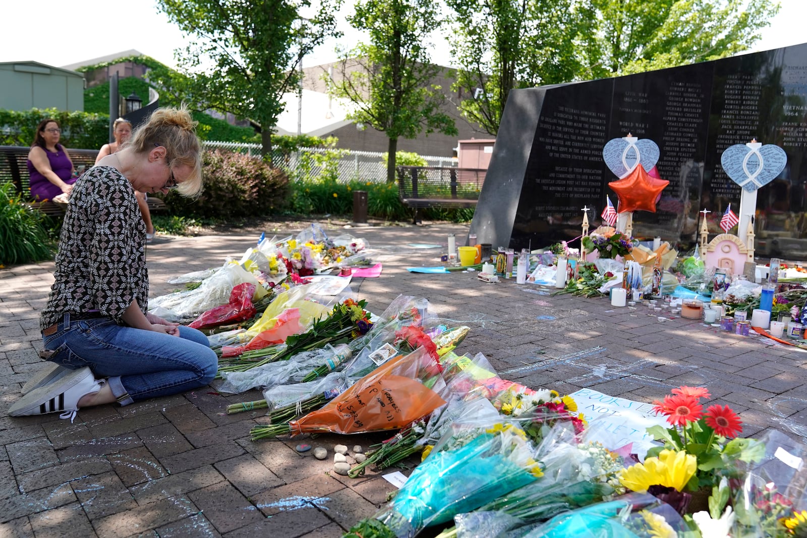 FILE - A visitor prays at a memorial to the seven people killed and others injured in the Fourth of July mass shooting at the Highland Park War Memorial in Highland Park, Ill., Thursday, July 7, 2022. (AP Photo/Nam Y. Huh, File)