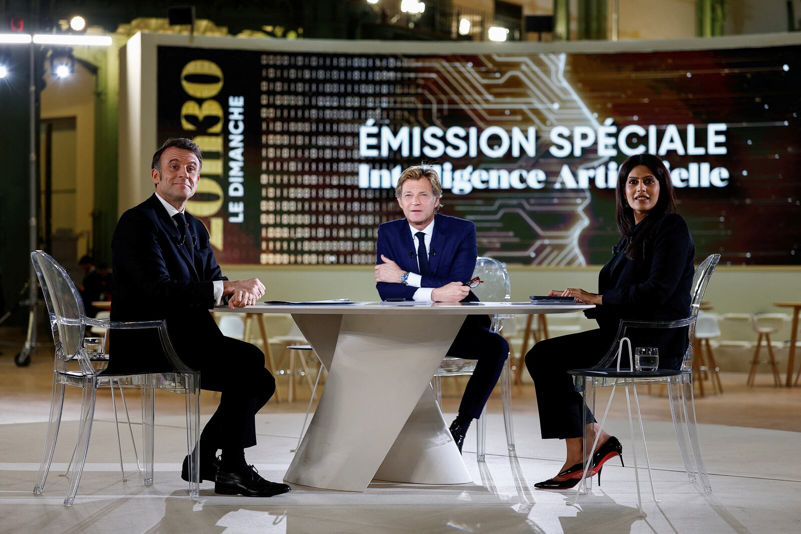 French President Emmanuel Macron, left, attends an interview with French Journalist Laurent Delahousse and Indian Journalist Palki Sharma Upadhyay, on national television, ahead of the Artificial Intelligence Action Summit at the Grand Palais in Paris, Sunday, Feb. 9, 2025. (Gonzalo Fuentes, Pool Photo via AP)