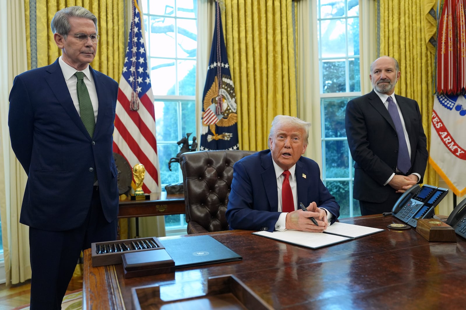 President Donald Trump speaks as Treasury Secretary Scott Bessent, left, and Commerce Secretary Howard Lutnick listen as Trump prepares to sign an executive order in the Oval Office of the White House, Monday, Feb. 3, 2025, in Washington. (AP Photo/Evan Vucci)