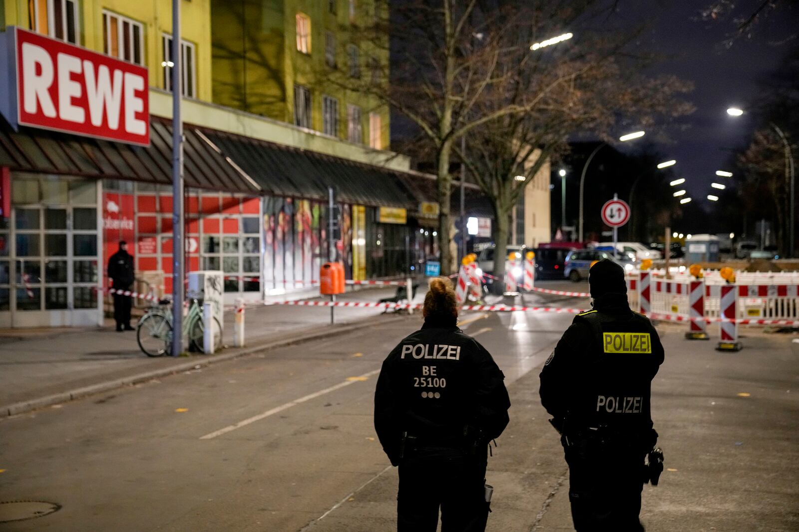 Police officers stand guard in front of a Rewe Market after a knife attack, in Berlin, Germany, Tuesday, Dec. 31, 2024. (AP Photo/Ebrahim Noroozi)