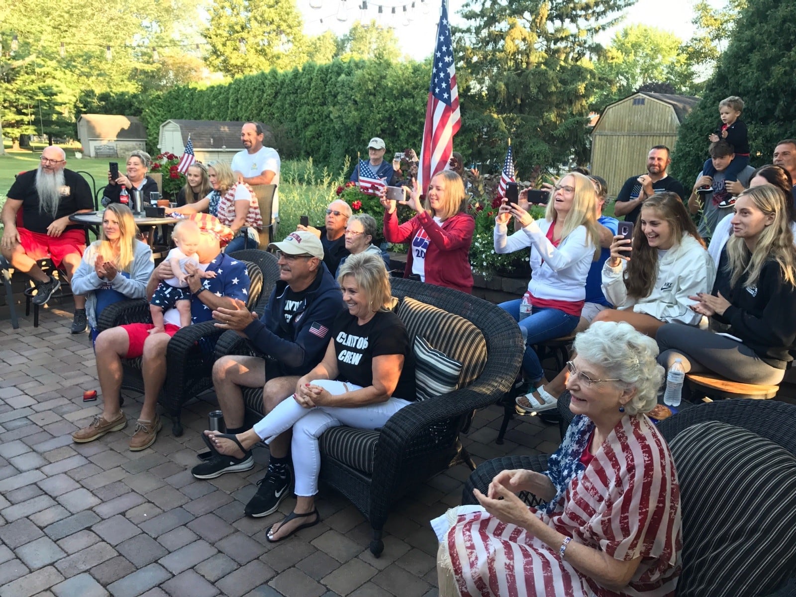 Mark Murphy (seated center, white cap) and his wife Christal (black shirt)  and his mother Wilma (on right in red and white striped top) watch early Wednesday morning with friends, neighbors and relatives as Mark’s son, Clayton, a Tri-Village High grad and bronze medalist in the 2016 Olympics, is introduced before the 800-meter final in Tokyo. The family had a Watch Party at their Piqua home. Boxed in early, Clayton finished, last of nine runners, after posting some of the fastest times in the preliminary heat and semi-final races. Photo by Tom Archdeacon