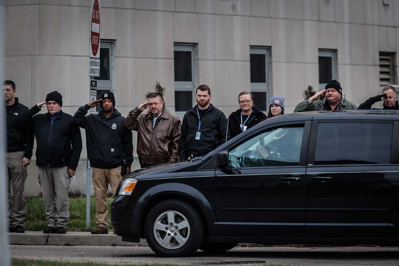 Dayton police officers and other city employees salute, as a Clark County Sheriff deputy who died is brought to the Montgomery County Coroner's Office on West Third Street in Dayton on Thursday, Dec. 19. 2024. JIM NOELKER/STAFF