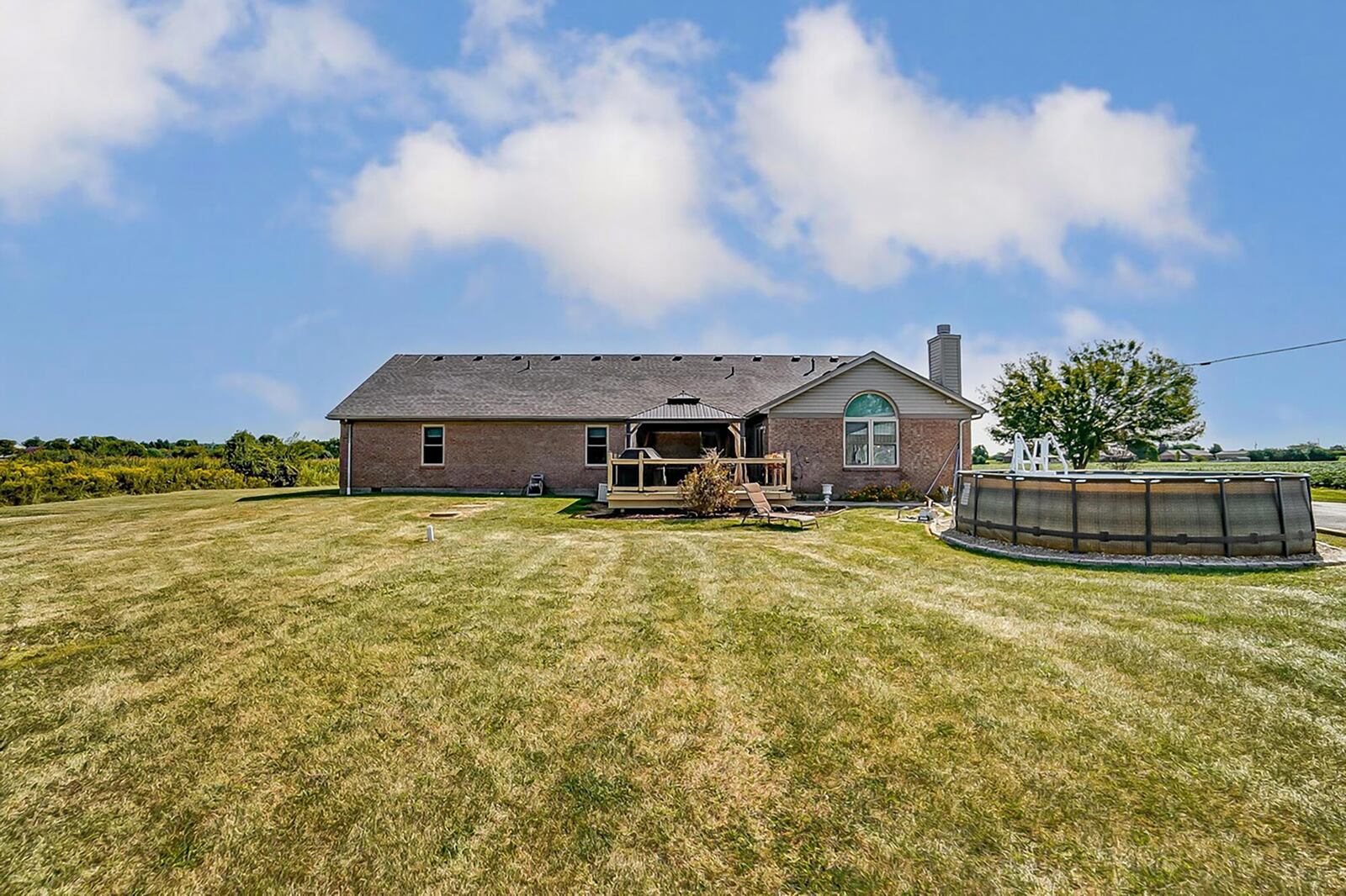 The rear of the home has a covered wood deck, above ground pool and detached one car garage/outbuilding.