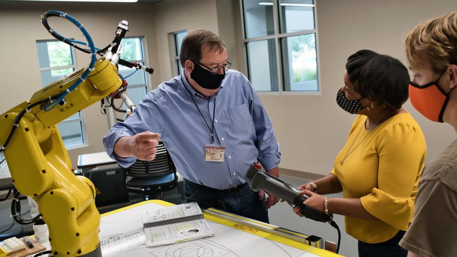 Workforce training is key to filling Ohio's top jobs with skilled employees. Wesley Evans, program coordinator for the Sinclair Community College Electronics Engineering Technology Department, demonstrates robotics to students inside the advanced manufacturing lab at the Courseview Campus in Mason.