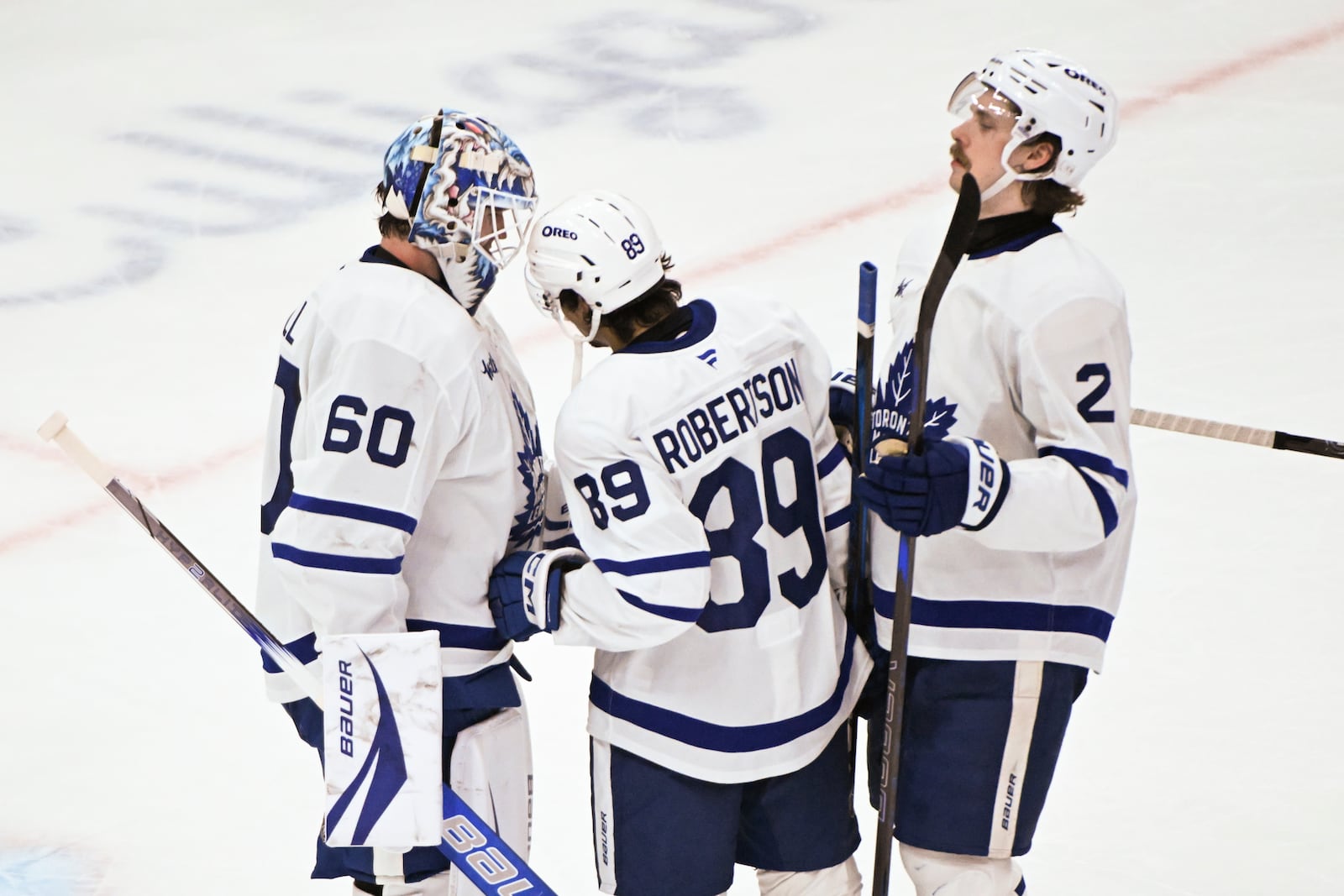 Toronto Maple Leafs goaltender Joseph Woll (60) celebrates with left wing Nicholas Robertson (89) and defenseman Simon Benoit (2) after an NHL hockey game against the Chicago Blackhawks, Sunday, Feb. 23, 2025, in Chicago. (AP Photo/Matt Marton)