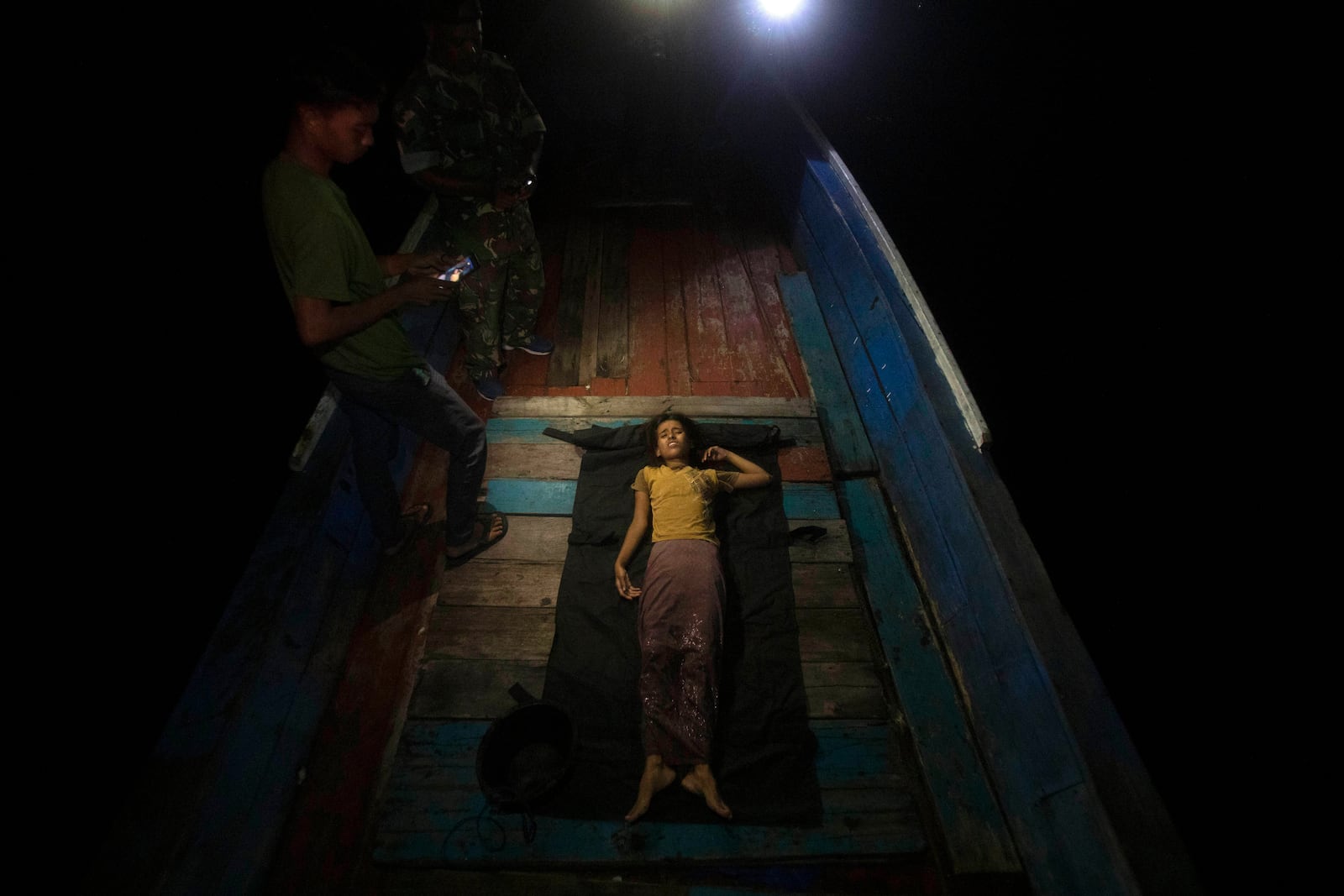 A young girl lies on the deck of a boat carrying Rohingya Muslims as she waits for a paramedic to check on her condition in the waters near the coast of Labuhan Haji, Aceh province, Indonesia, Tuesday, Oct. 22, 2024. (AP Photo/Binsar Bakkara)