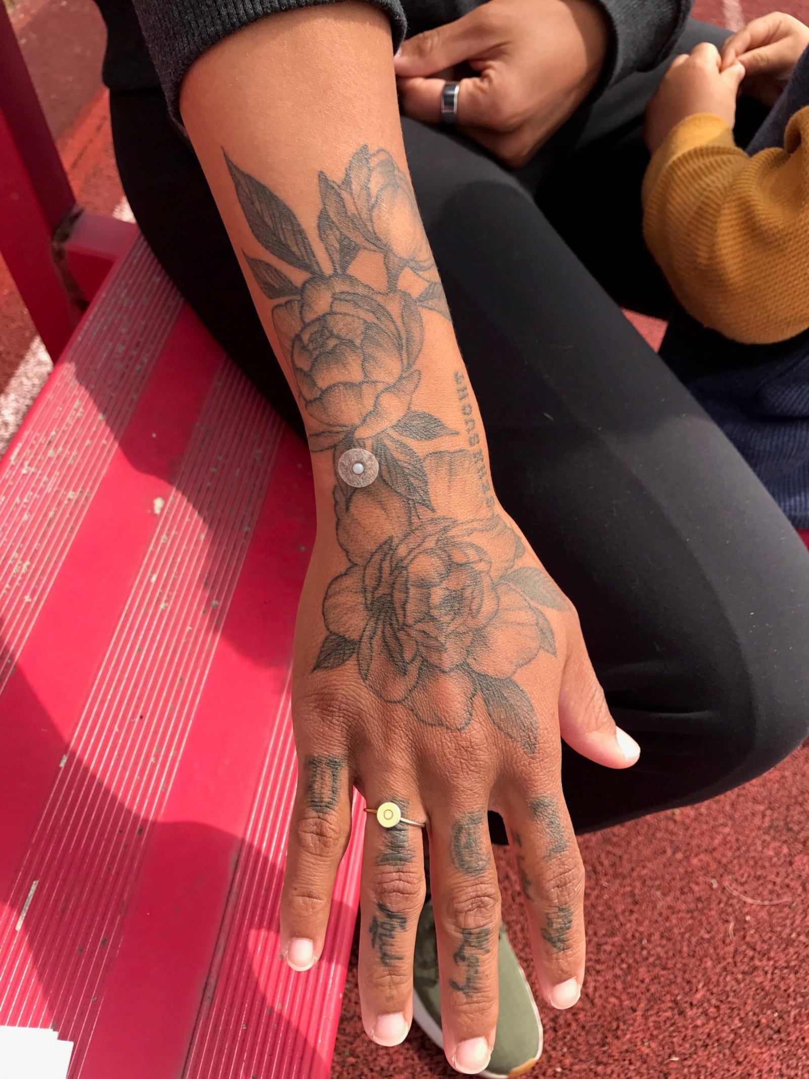 Chantae McMillan with the peonies tattooed on her arm as a reminder of her late father, Badger McMillan – an Army veteran and ardent supporter of his daughter – who favored the old-time flowers and always cut some they had at their home in Missouri for a Mother’s Day bouquet. The circular button near her wrist is for acupuncture treatments.  (Photo by Tom Archdeacon)