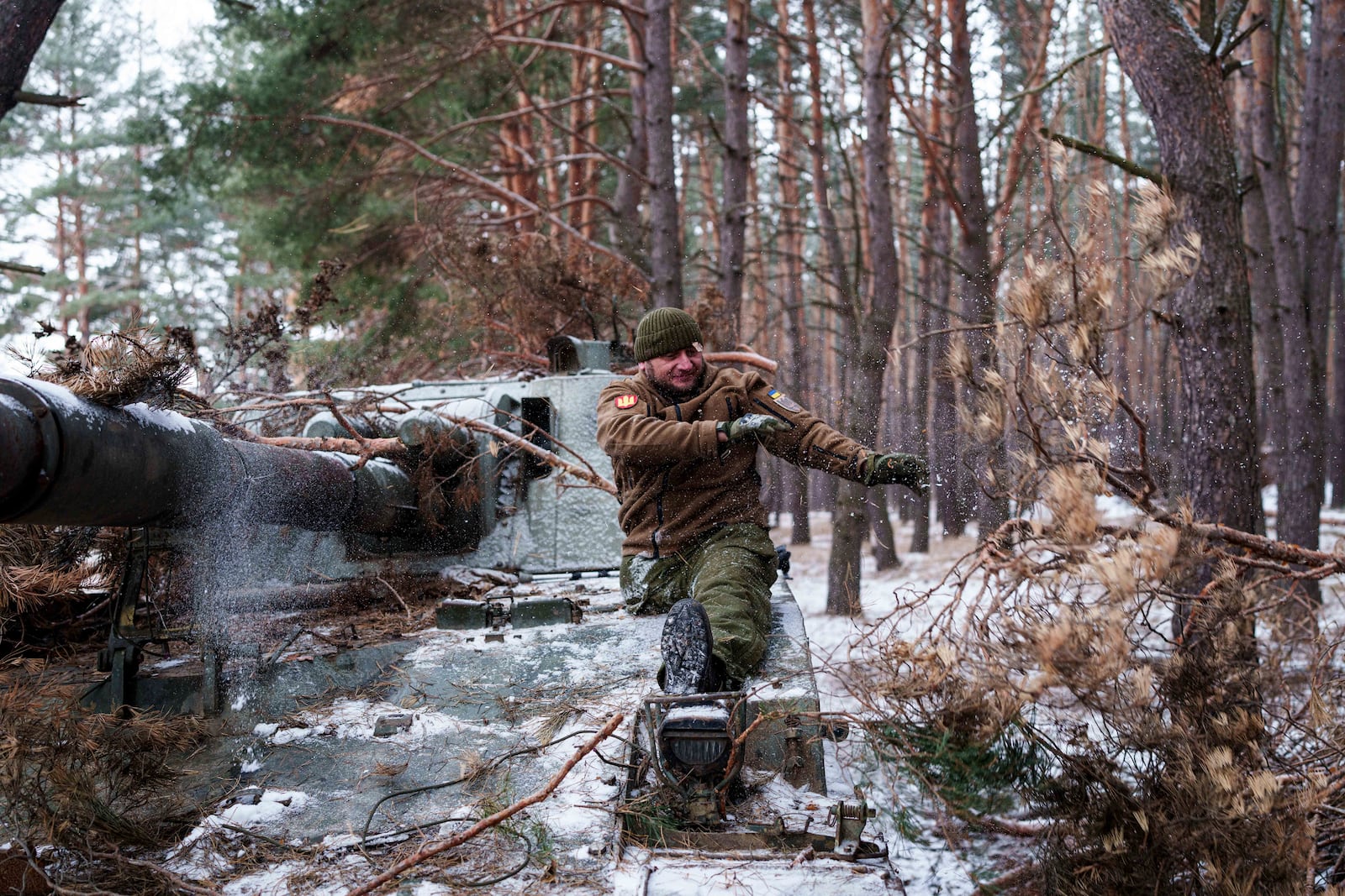 Leonid Lobchuk, a soldier with Ukraine's 127th brigade who lost a leg in combat in eastern Ukraine in 2015, takes the camouflage off his self-propelled howitzer in Ukraine's Kharkiv region on Feb. 10, 2025. (AP Photo/Evgeniy Maloletka)