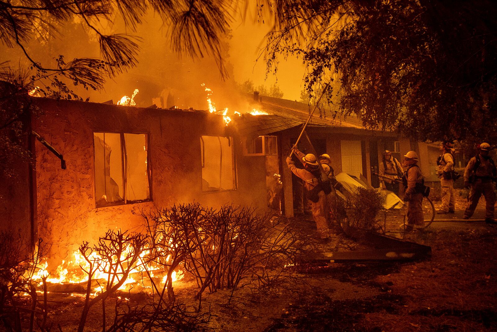 FILE - Firefighters work to keep flames from spreading through the Shadowbrook apartment complex as a wildfire burns through Paradise, Calif., on Nov. 9, 2018. (AP Photo/Noah Berger, File)