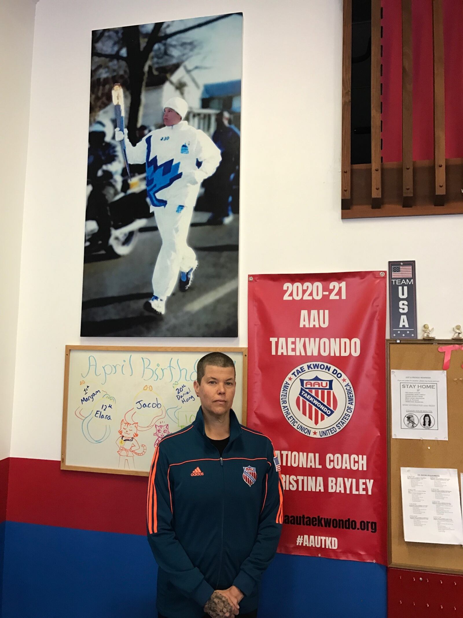 Christina Bayley at her school on Stroop Road – Total Taekwondo and Fitness – with banner designating her the National AAU Taekwondo Coach of the Year and a photo of her carrying the Olympic Torch before the first post 9/11 Olympic Games, the 2022 Winter Olympics in Salt Lake City, Utah. Tom Archdeacon/STAFF