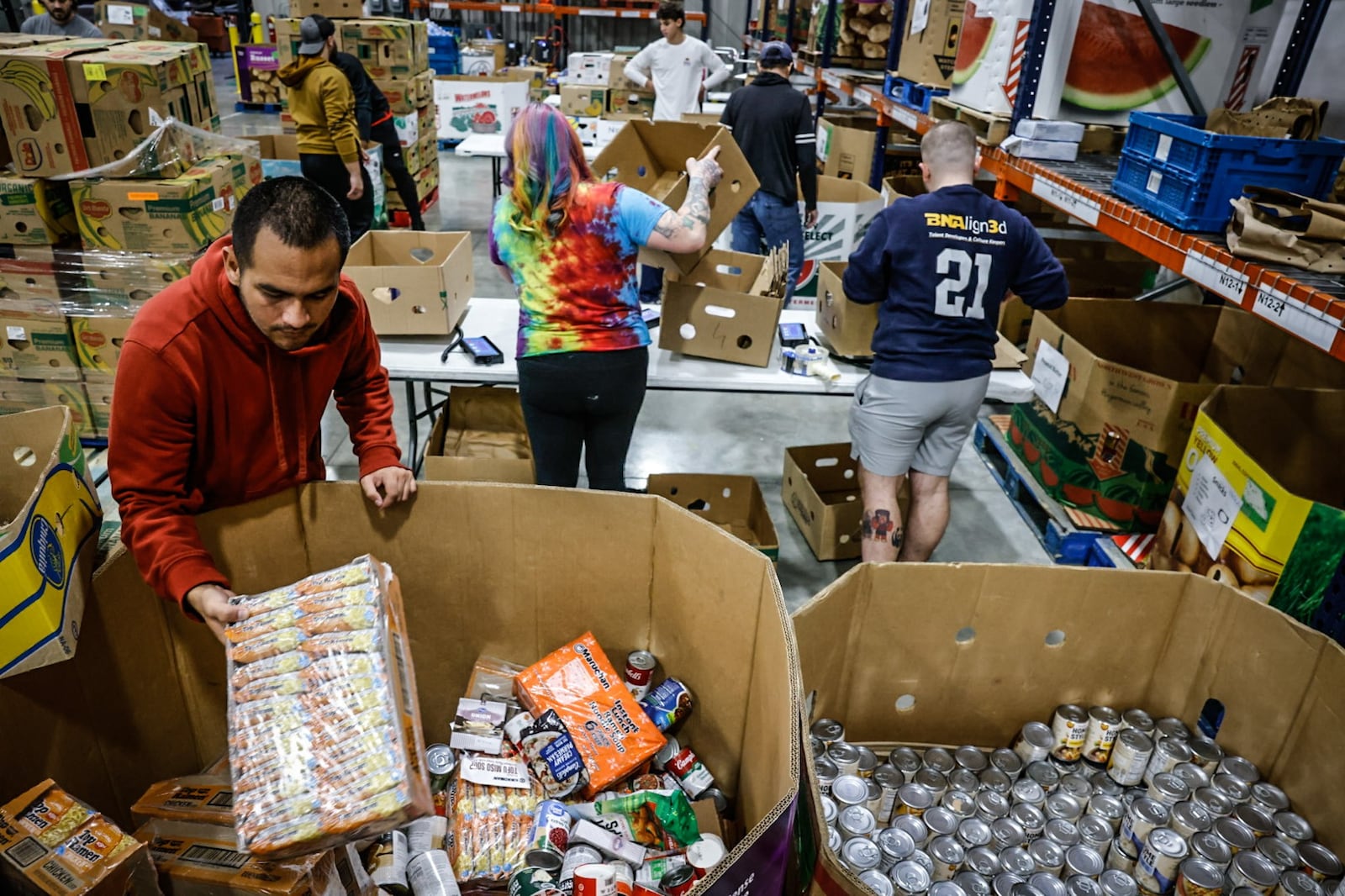 Foodbank Inc. volunteer Josh Ortiz, left box-up food for area senior at the warehouse Thursday November 7, 2024. JIM NOELKER/STAFF