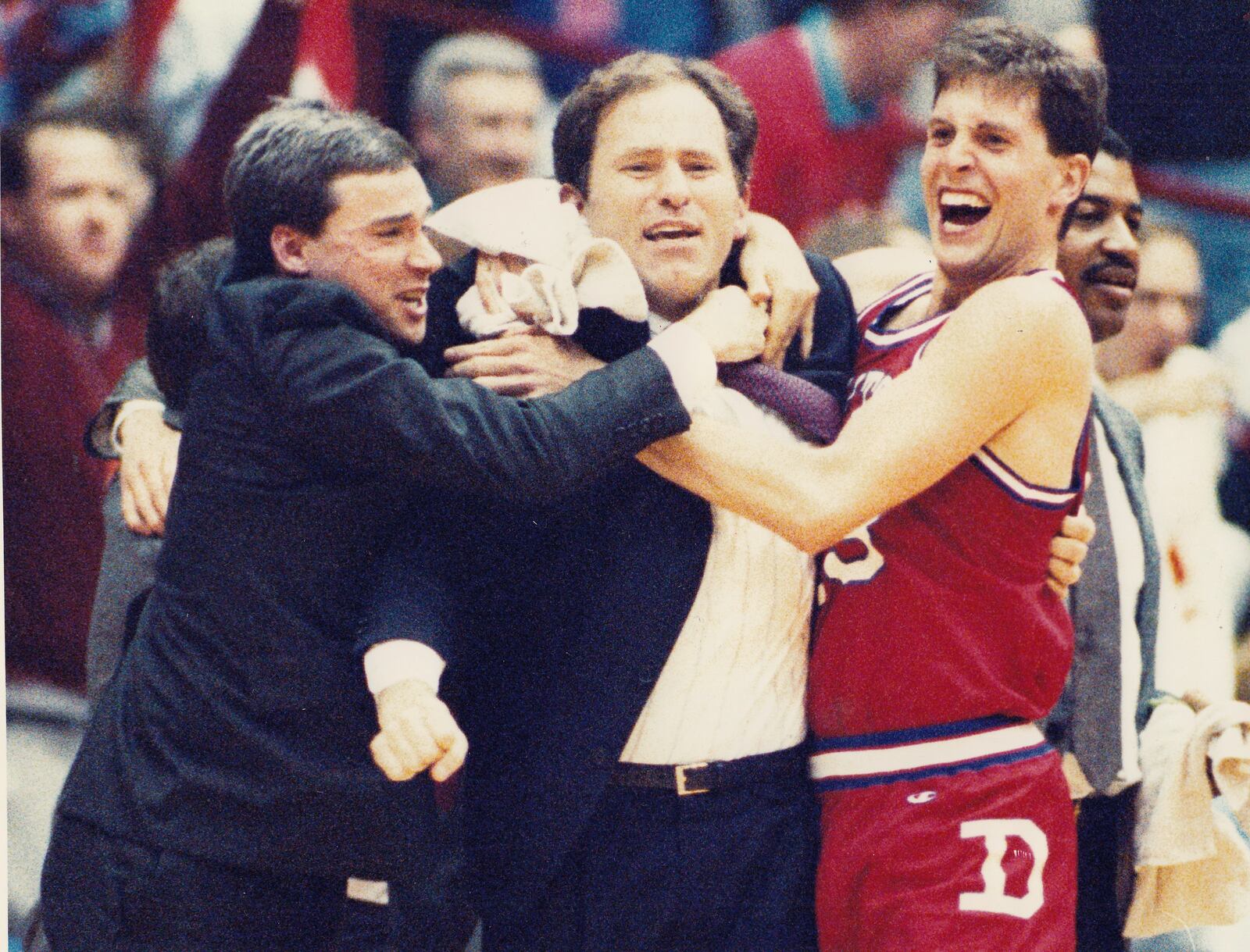 Dayton assistant coach Tom McConnell, left, and Norm Grevey, right, hug head coach Jim O’Brien in the final seconds of a victory against Xavier in the Midwestern Collegiate Conference tournament championship game in 1990 at UD Arena. Dayton Daily News photo by Jan Underwood