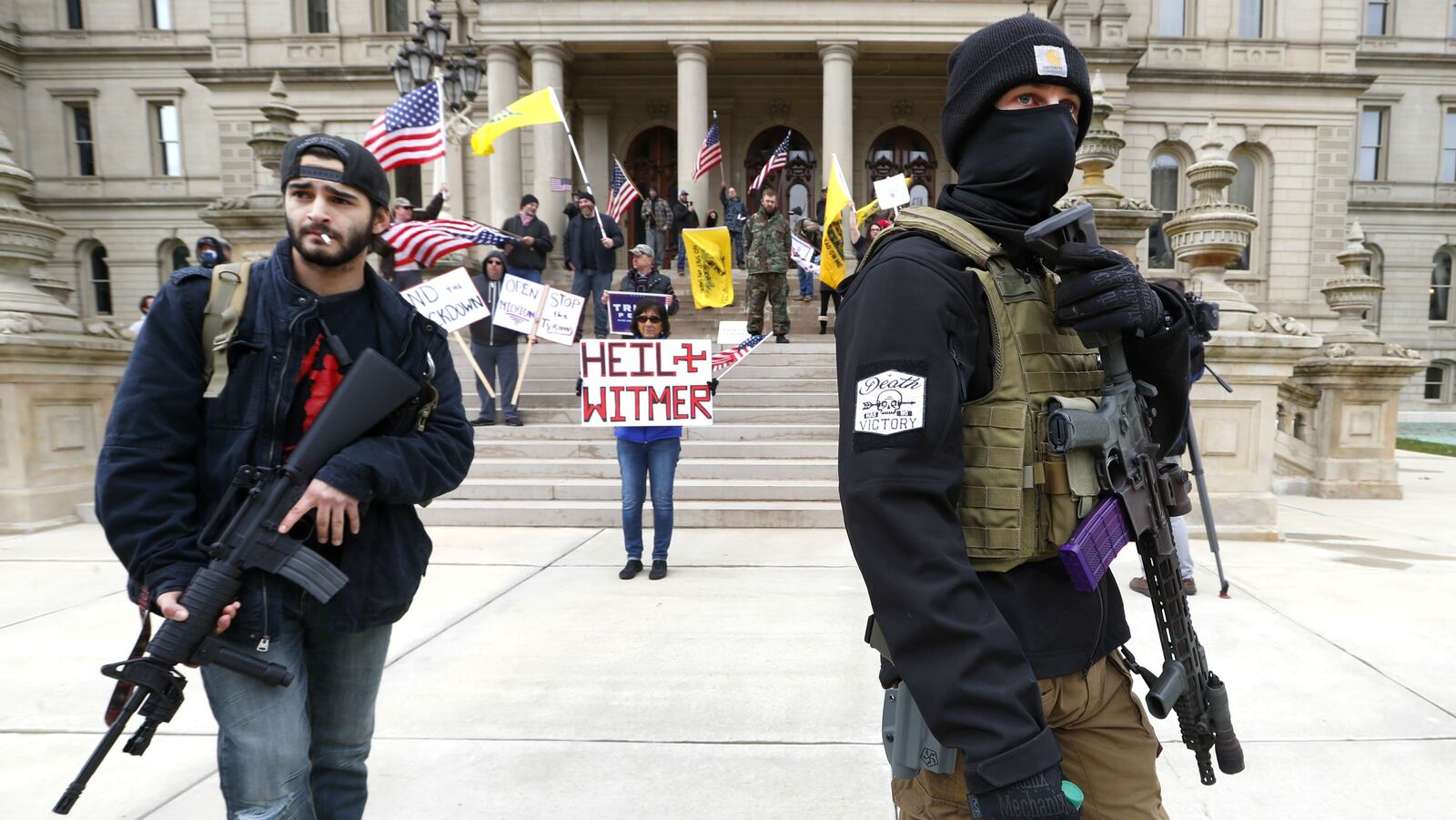 Protesters carry rifles outside the Michigan State Capitol in Lansing, Mich., April 15, 2020. Armed citizens unhappy with Gov. Gretchen Whitmer's coronavirus lockdown have spent weeks protesting the measures.