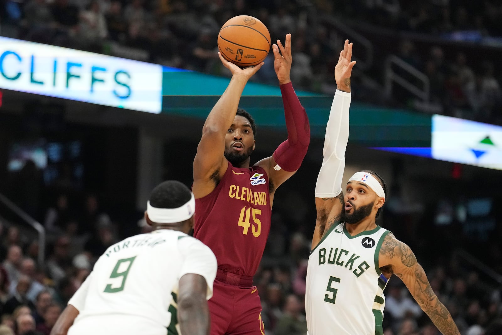 Cleveland Cavaliers guard Donovan Mitchell (45) shoots between Milwaukee Bucks forward Bobby Portis Jr. (9) and guard Gary Trent Jr. (5) in the first half of an NBA basketball game, Monday, Nov. 4, 2024, in Cleveland. (AP Photo/Sue Ogrocki)