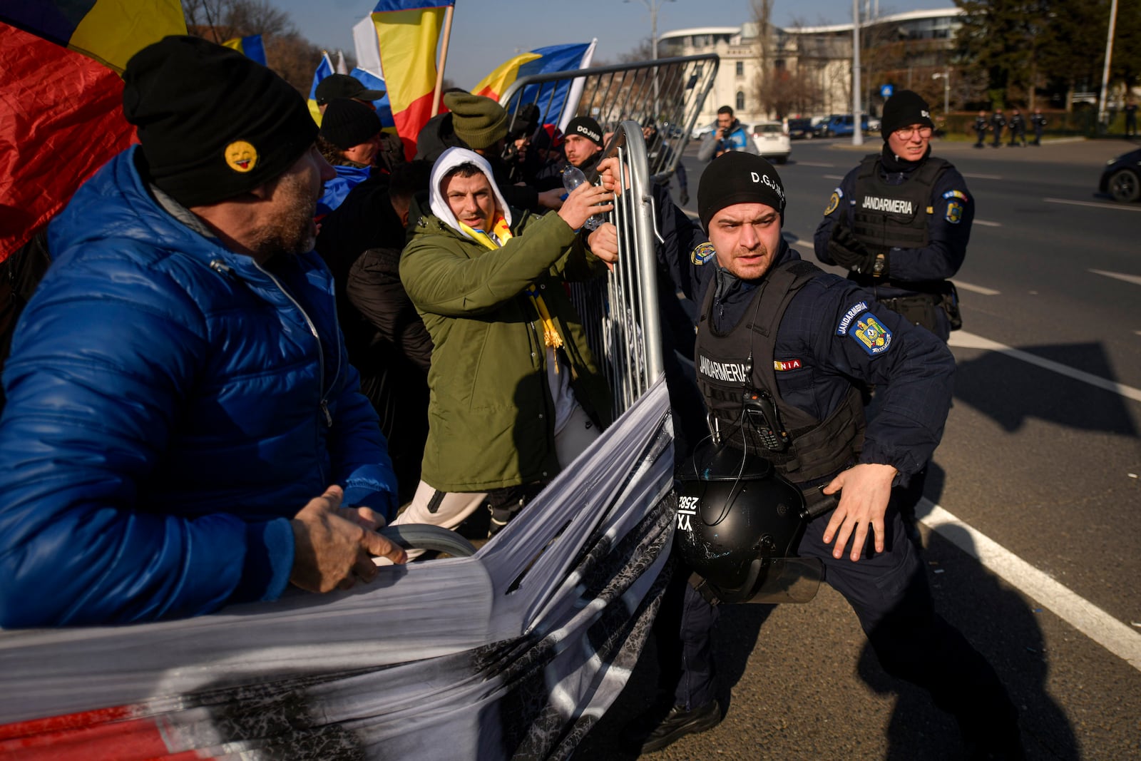 Riot police scuffle with supporters of Calin Georgescu, the winner of Romania's first round of presidential election which the Constitutional Court later annulled, who broke through police lines in front of the government headquarters, in Bucharest, Romania, Monday, Feb. 10, 2025. (AP Photo/Alexandru Dobre)