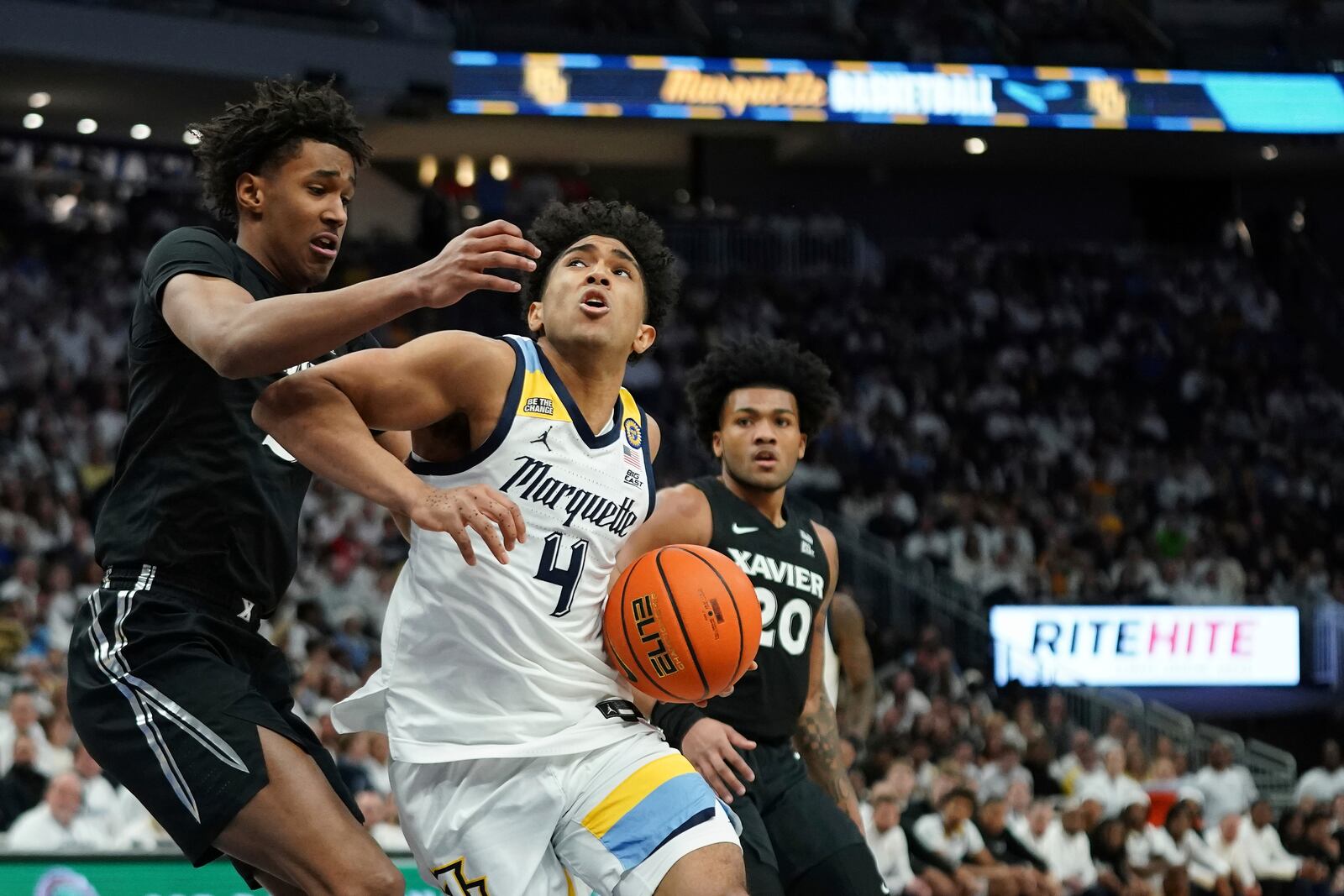 Marquette's Stevie Mitchell (4) drives to the basket against Xavier's Dailyn Swain during the first half of an NCAA college basketball game Saturday, Jan. 18, 2025, in Milwaukee. (AP Photo/Aaron Gash)