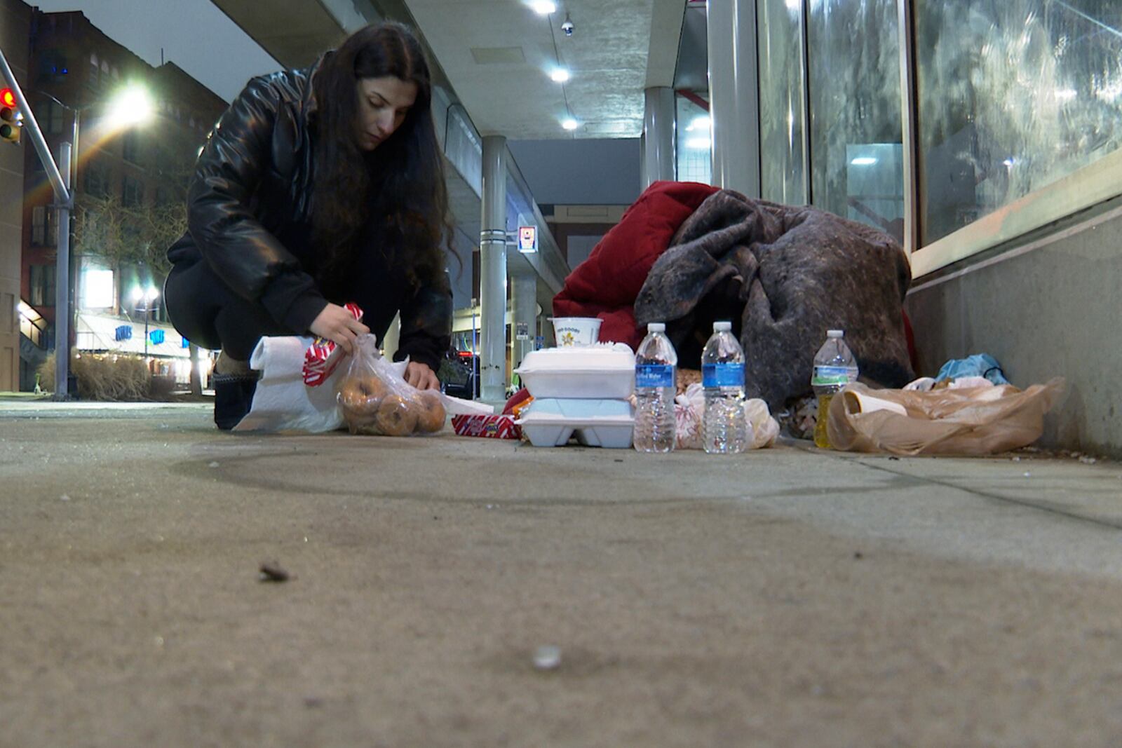 In this image from video, The Helping Handzzz Foundation board member Mariam Hachem provides a food donation to a homeless person Friday, March 7, 2025, in Detroit (AP Photo/Mike Householder)