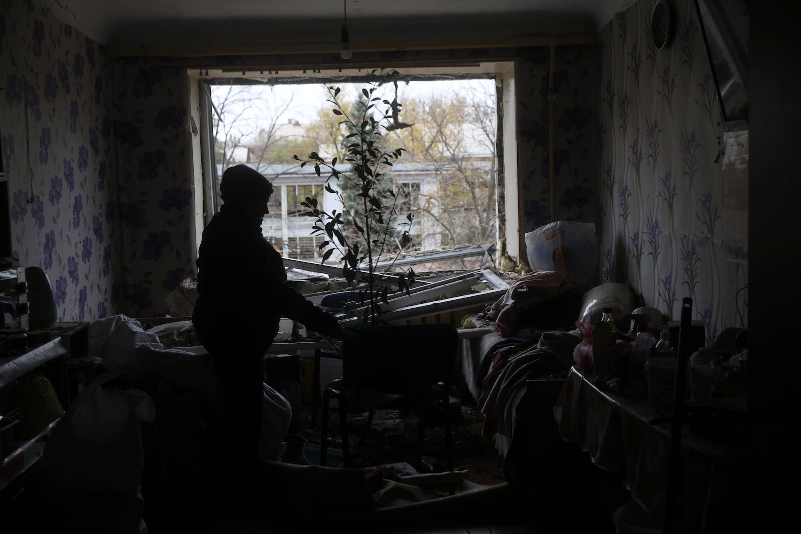 A woman clear the rubble inside her apartment at a hostel for displaced persons damaged by a Russian strike in Zaporizhzhia, Ukraine, Nov. 11, 2024. (AP Photo/Kateryna Klochko)