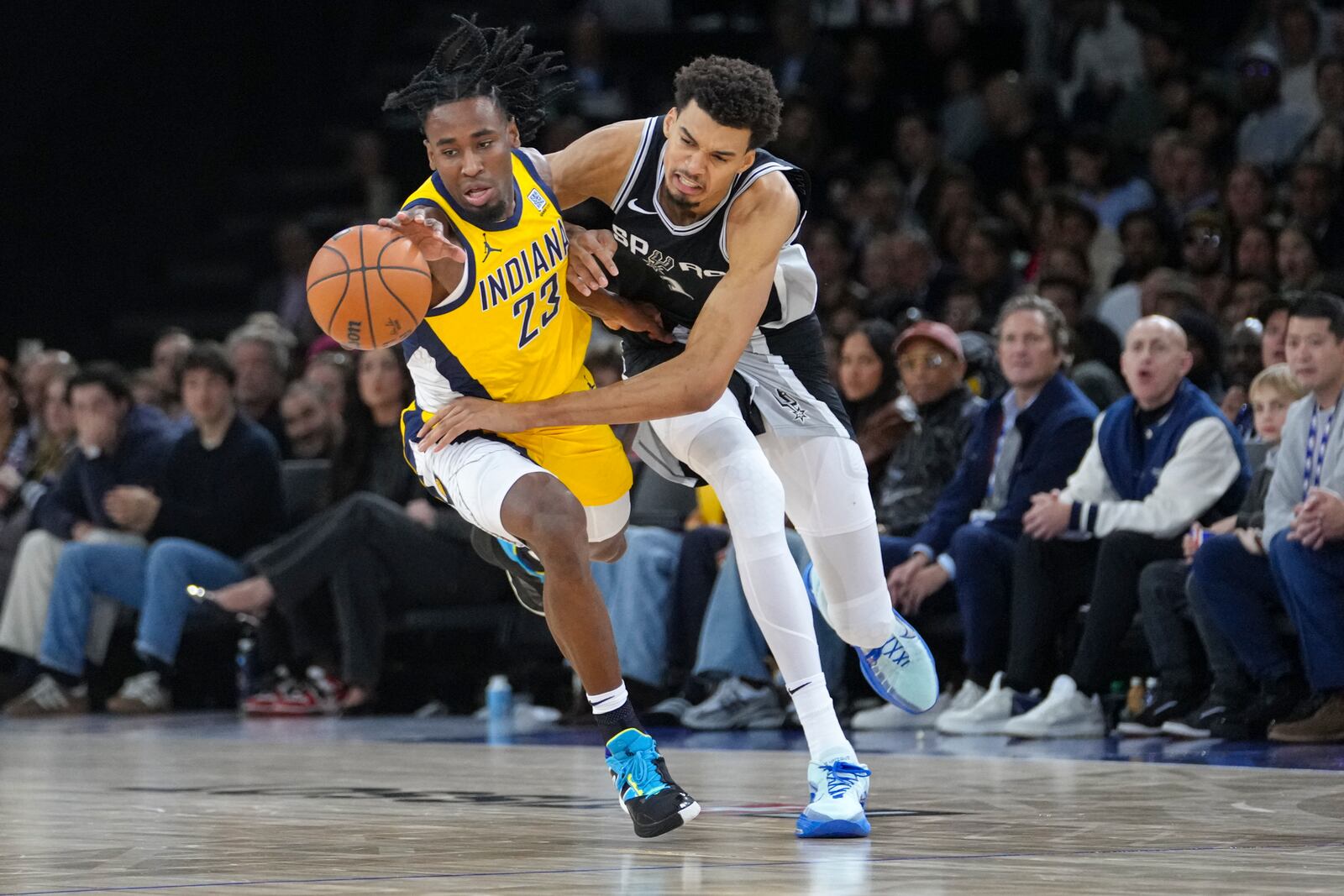 San Antonio Spurs center Victor Wembanyama (1) and Indiana Pacers forward Aaron Nesmith (23) get tangled up as they go for a loose ball during the second half of a Paris Games 2025 NBA basketball game in Paris, Saturday, Jan. 25, 2025. (AP Photo/Thibault Camus)