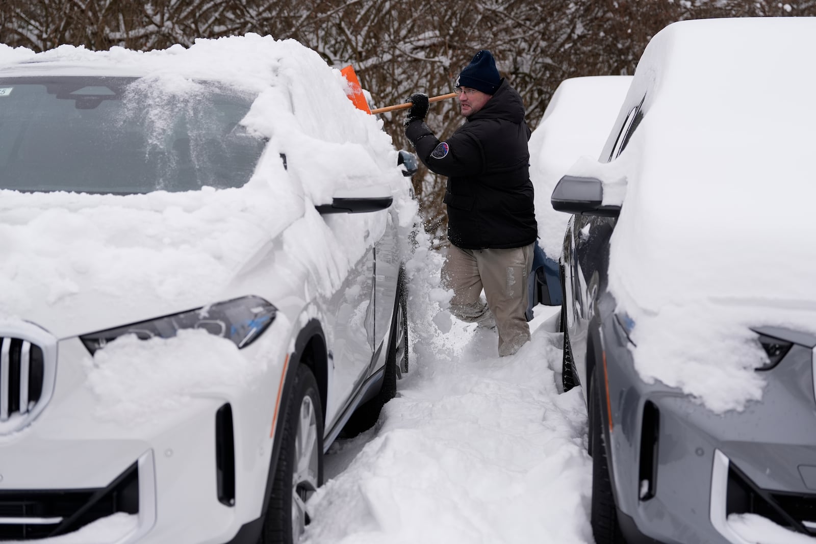 The BMW Store lot technician Cary Fallath clears snow from new BMWs in Silverton, Ohio, Tuesday, Jan. 7, 2025. (AP Photo/Carolyn Kaster)