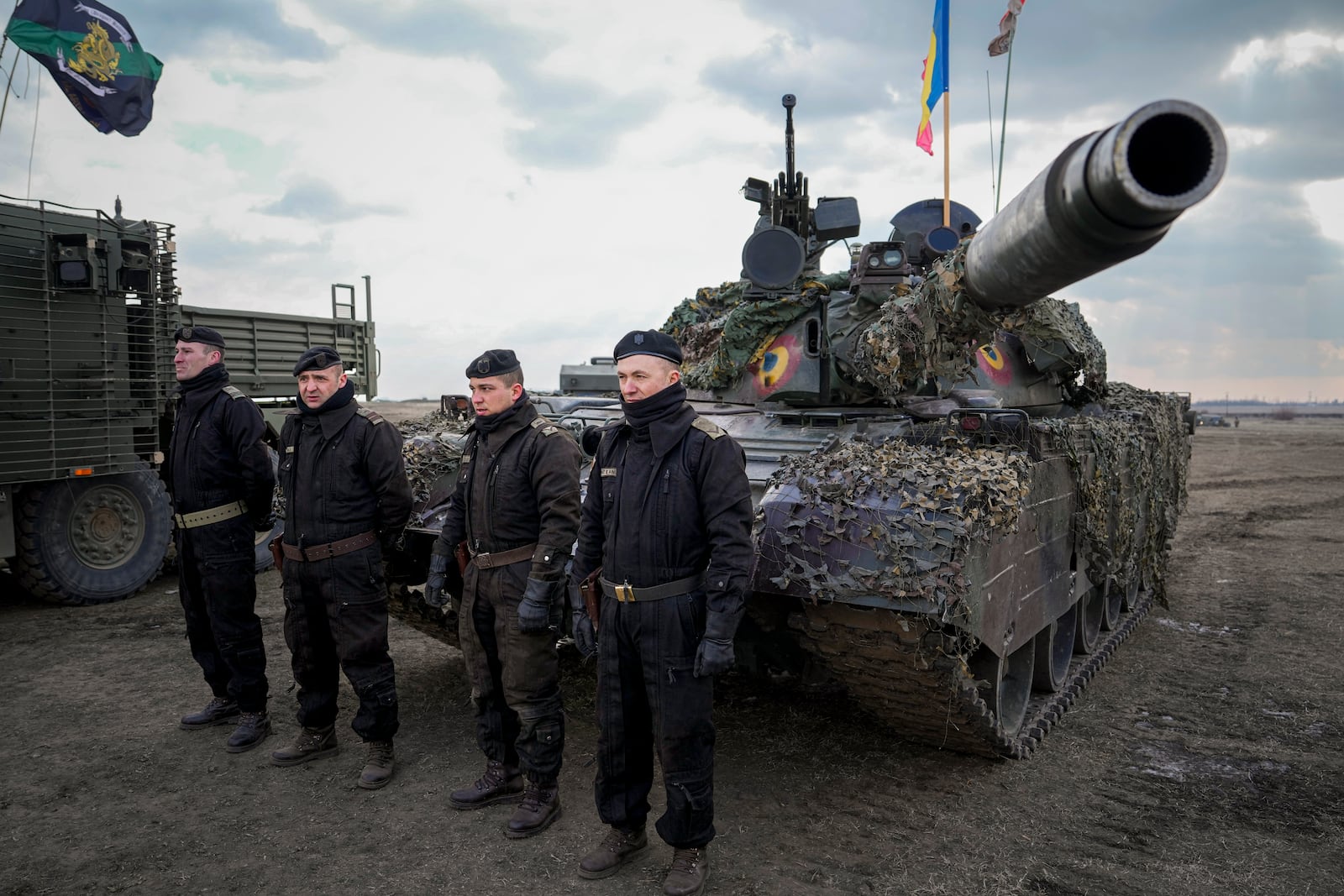 Romanian servicemen sit in front of a tank at the end of the Steadfast Dart 2025 exercise, involving some 10,000 troops in three different countries from nine nations and represent the largest NATO operation planned this year, at a training range in Smardan, eastern Romania, Wednesday, Feb. 19, 2025. (AP Photo/Vadim Ghirda)