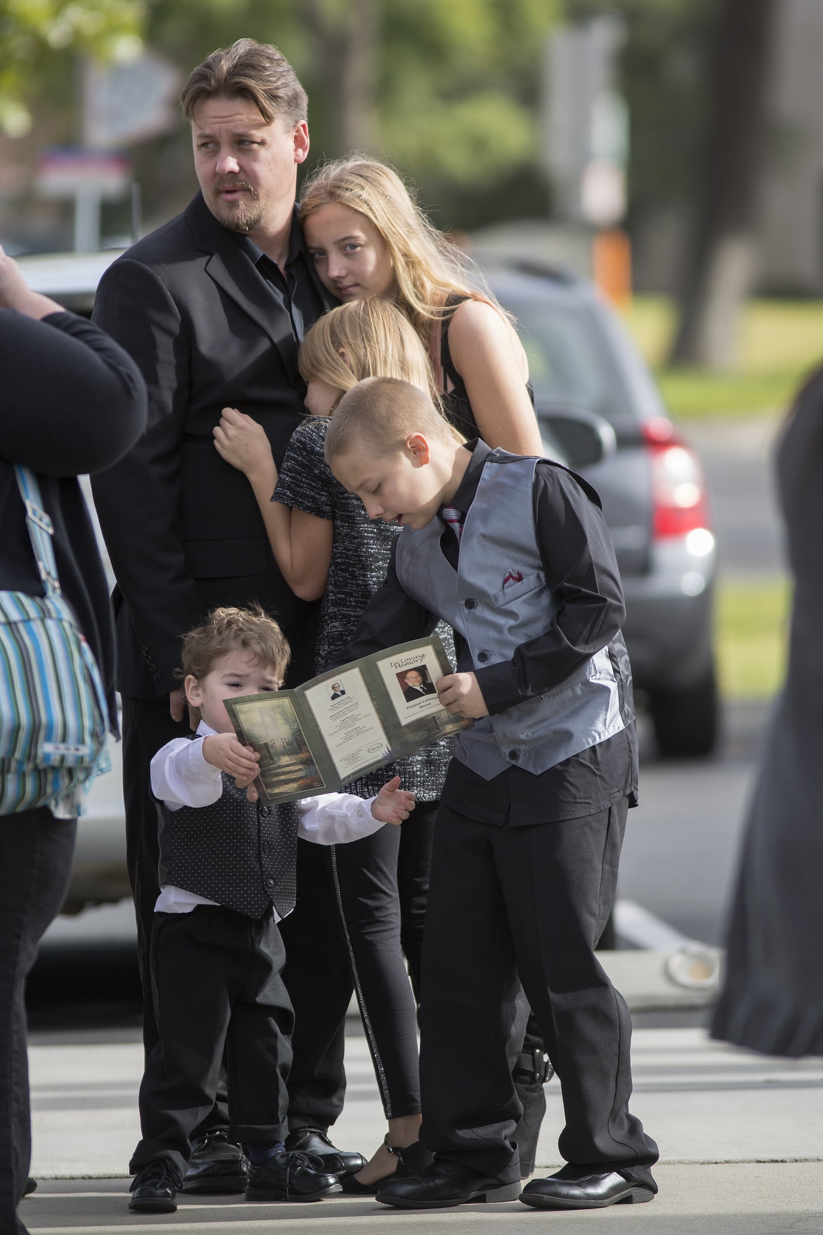 Mourners hug and children look at a funeral program before the start of funeral services for Damian Meins, who died in the December 2015 massacre in San Bernardino, on Dec. 11, 2015 in Riverside, Calif. (Photo by David McNew/Getty Images)