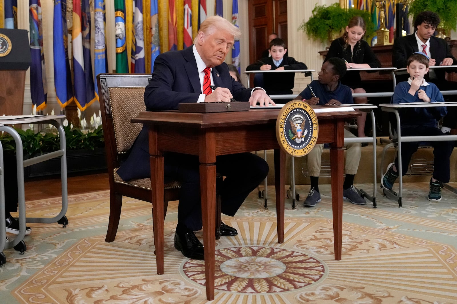 President Donald Trump signs an executive order in the East Room of the White House in Washington, Thursday, March 20, 2025. (AP Photo/Ben Curtis)