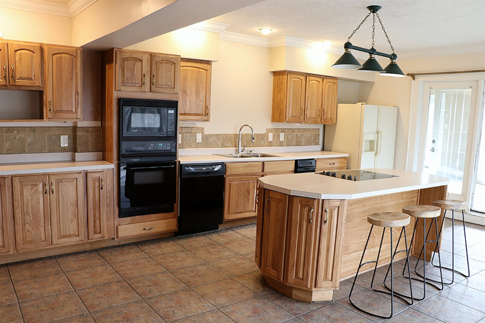 A spacious kitchen has a wall of oak pantry cabinets with pullout shelves. An island provides seating for four and has a cooktop. CONTRIBUTED PHOTO BY KATHY TYLER