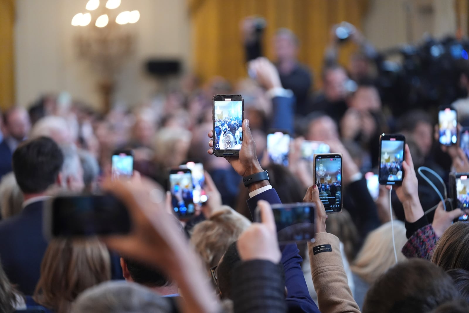 Personal cameras photograph President Donald Trump as he arrives to speak before signing an executive order barring transgender female athletes from competing in women's or girls' sporting events, in the East Room of the White House, Wednesday, Feb. 5, 2025, in Washington.(AP Photo/ Evan Vucci)