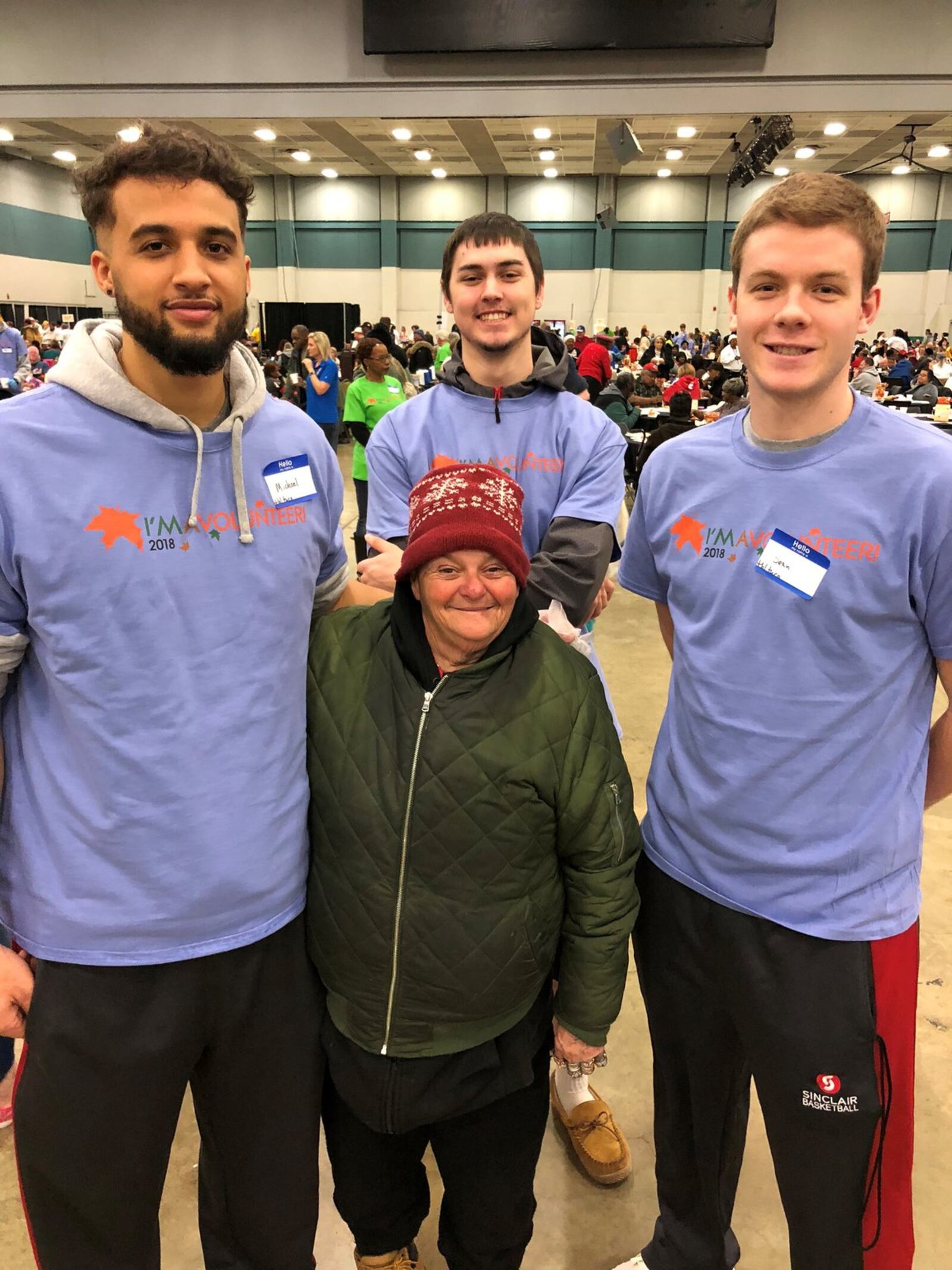 Sean McNeil (right) and teammates Michael Collier (left) and Cade Morgan (center) huddle around a woman who attended Thursday’s Feast of Giving at Dayton Convention Center. She requested a photo with “our heroes.” CONTRIBUTED