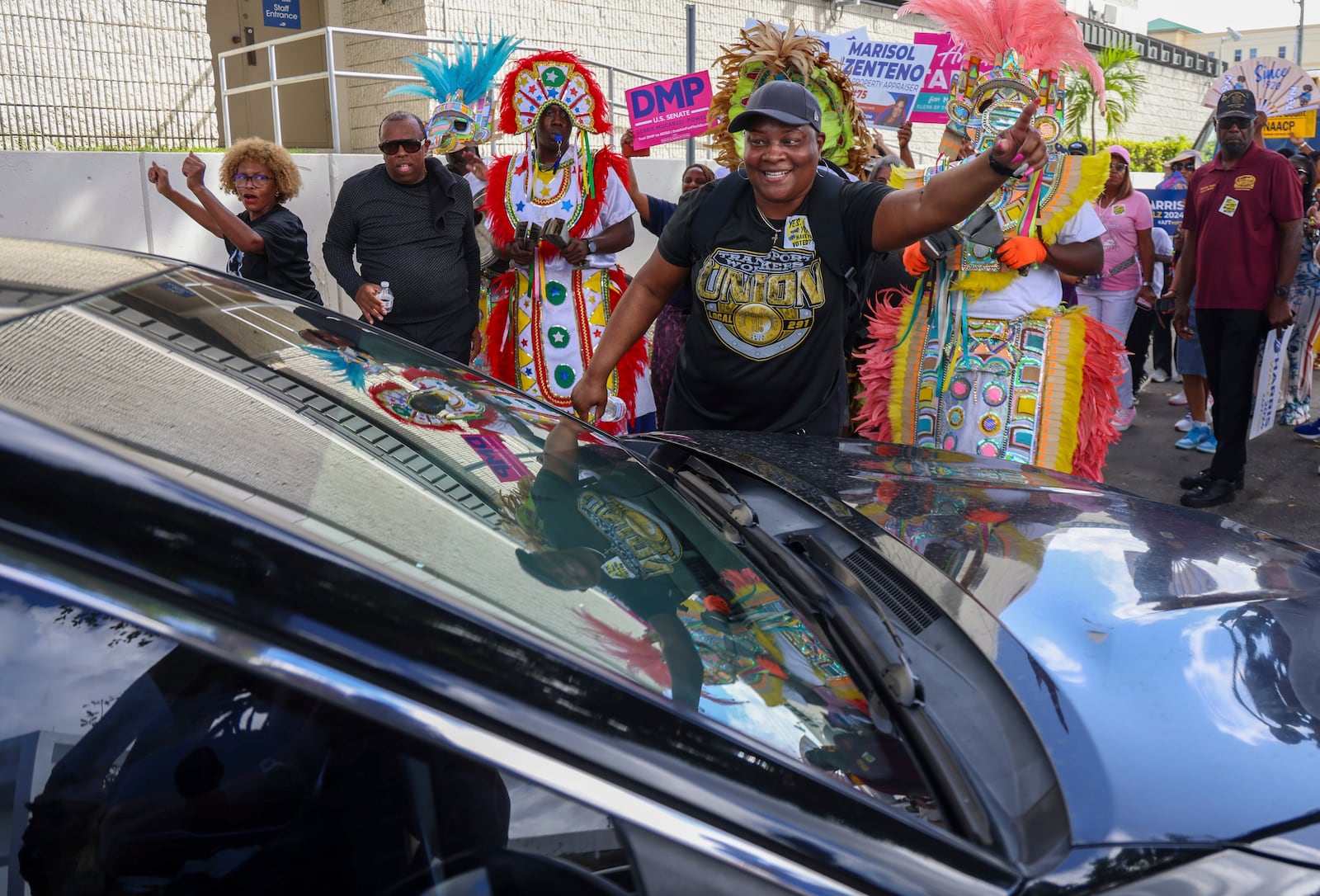 A poll worker assist a motorist out of the path the crowd as they marched and sang to the polls during the "Souls to the Polls" event on the last day of early voting on Sunday, Nov. 3, 2024, in Miami. (Carl Juste/Miami Herald via AP)