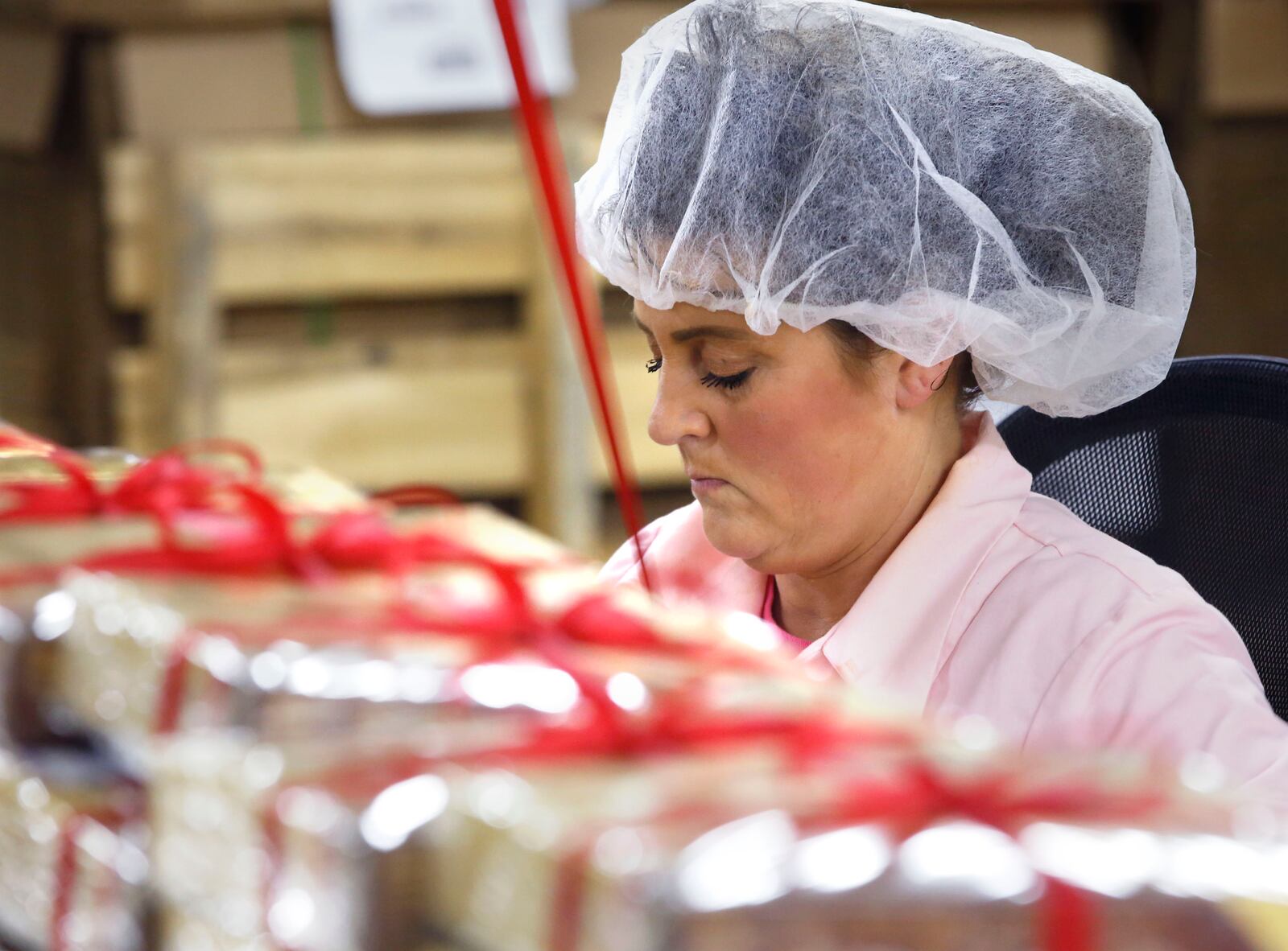 Crystal Schelling ties the signature red ribbon on boxes of Esther Price Candies.  TY GREENLEES / STAFF