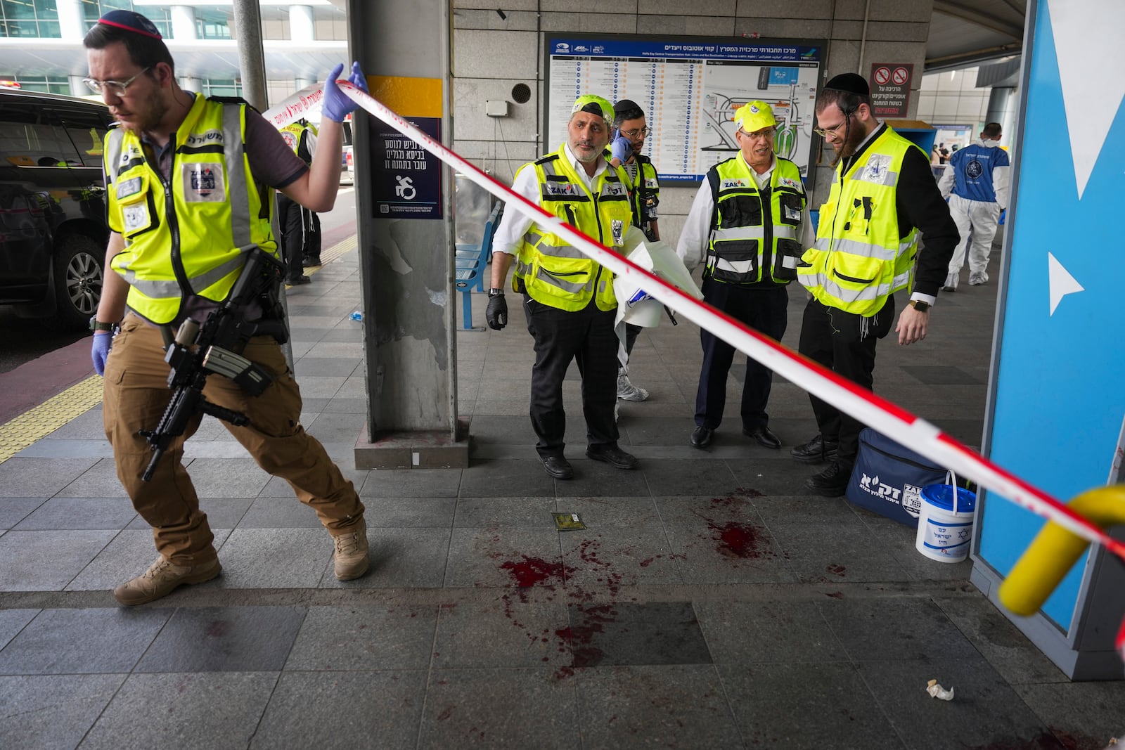 Members of ZAKA rescue services clean blood stains at the scene of a stabbing attack in Haifa, Israel, on Monday, March 30, 2025, where a 70-year-old man was killed and four others were injured. (AP Photo/Ariel Schalit)