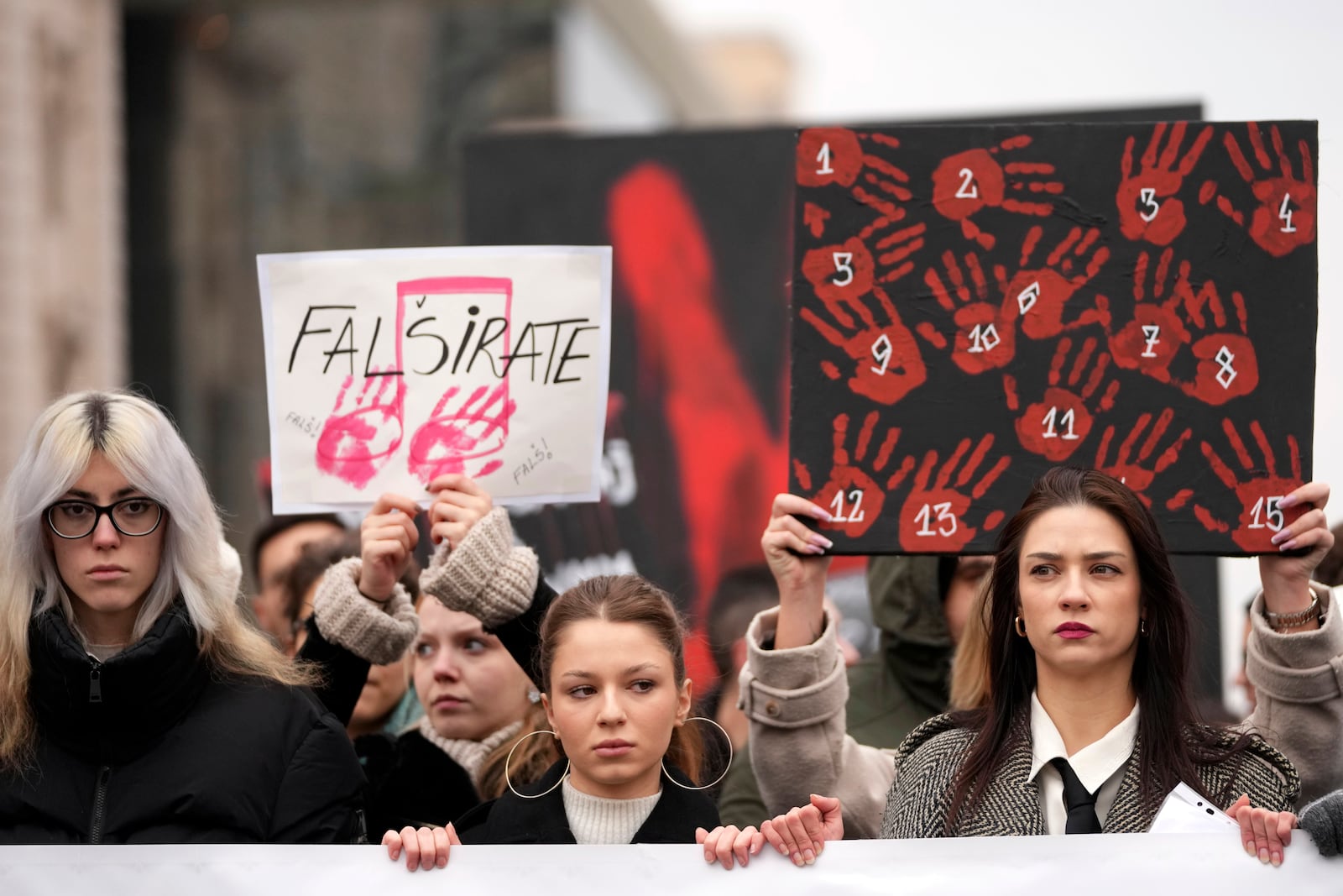 People stopping traffic hold placards and stand in silence to commemorate the 15 victims of a railway roof collapse six weeks ago, demand accountability for the tragedy, in Belgrade, Serbia, Friday, Dec. 13, 2024. (AP Photo/Darko Vojinovic)