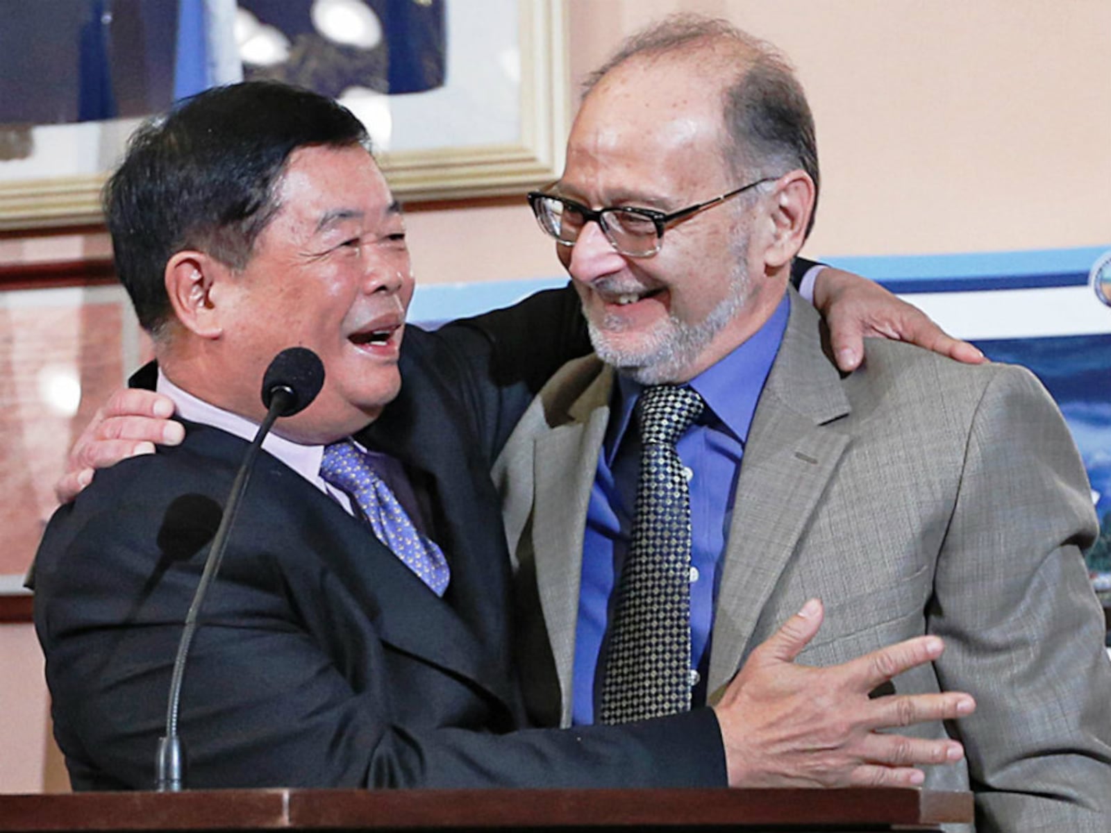 Company Chairman Cao Dewang, left, and plant site owner Stu Lichter shake hands and embrace to celebrate their deal after an announcement of a new manufacturing plant in Montgomery County in the Ohio Statehouse Cabinet Room on January 10, 2014. (Chris Russell/Dispatch Photo)