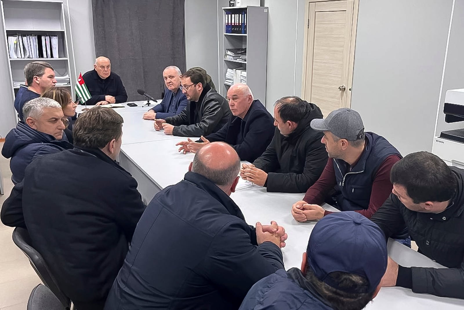 In this photo taken from video released by Information Center of the President of the Republic of Abkhazia on Monday, Nov. 18, 2024, Abkhazian President Aslan Bzhania, background second left, speaks to a group of Abkhazian lawmakers in the village of Tamishi, in Georgia’s breakaway province of Abkhazia. (Information Center of the President of the Republic of Abkhazia via AP)