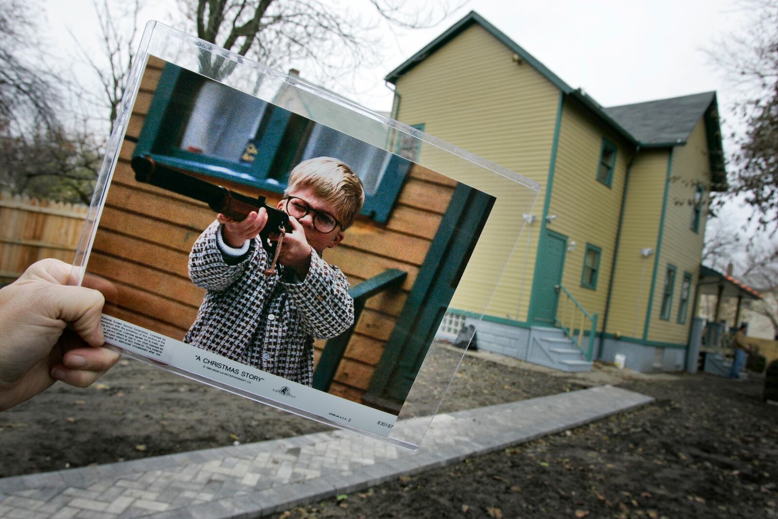 FILE - A photo of the character Ralphie, played by actor Peter Billigsley, firing his Red Ryder air rifle from the classic movie "A Christmas Story" is held in the back yard of the house used in the filming of the movie in Cleveland, Ohio, Nov. 13, 2006. (AP Photo/Amy Sancetta, File)